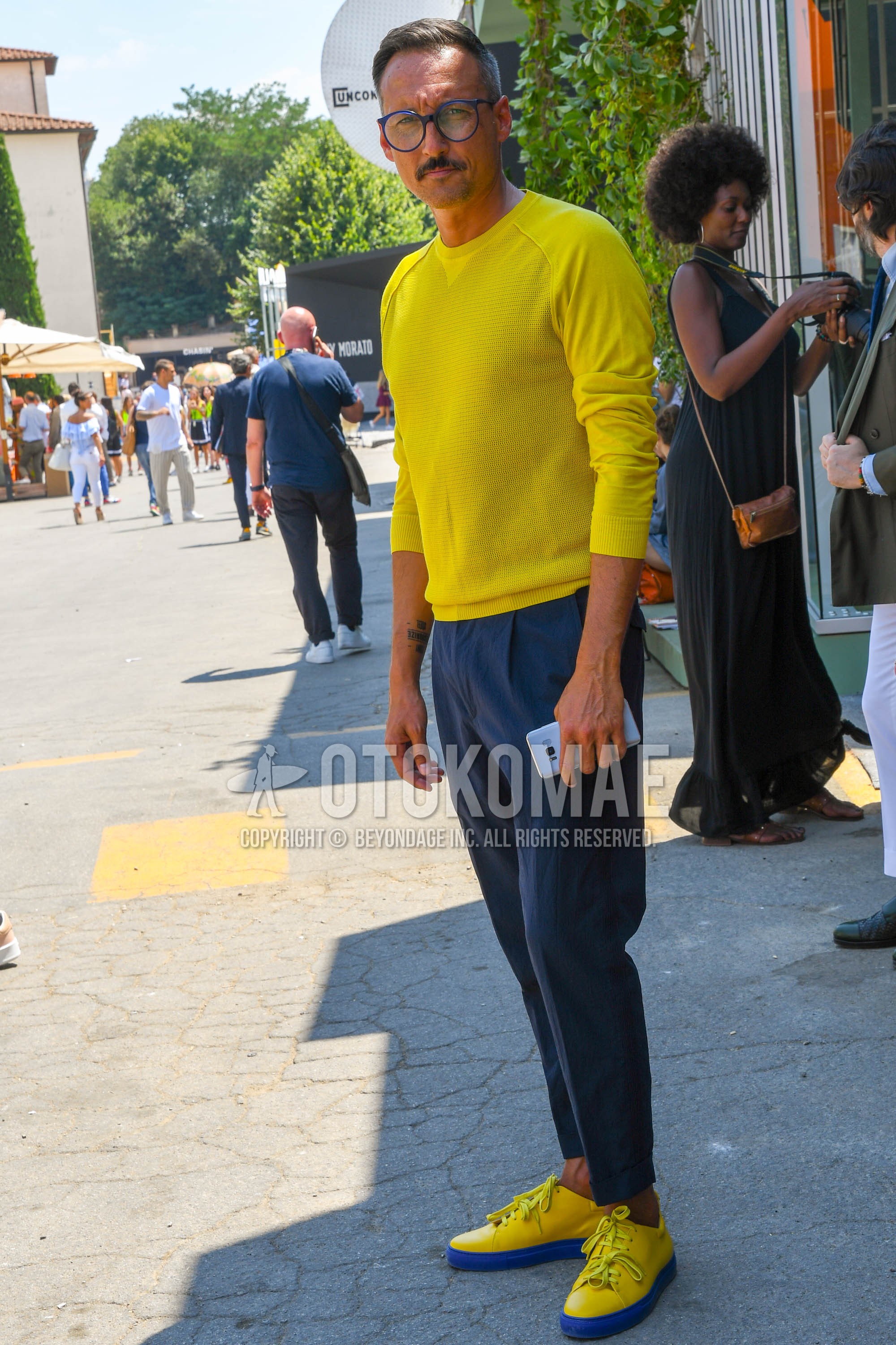 Men's spring summer outfit with blue plain glasses, yellow plain sweater, gray plain slacks, yellow low-cut sneakers.