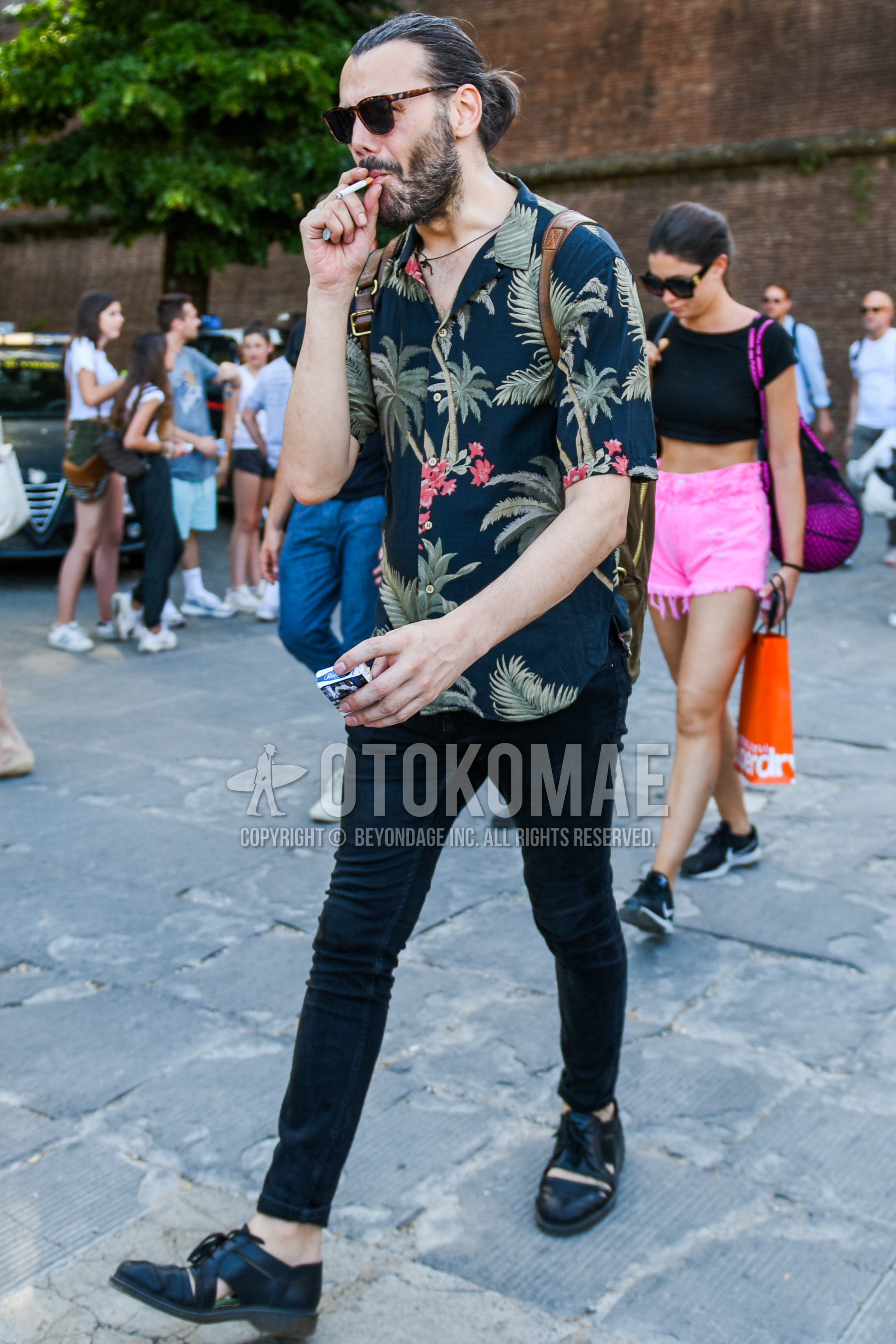 Men's summer outfit with brown tortoiseshell sunglasses, navy botanical shirt, black plain damaged jeans, black straight-tip shoes leather shoes.