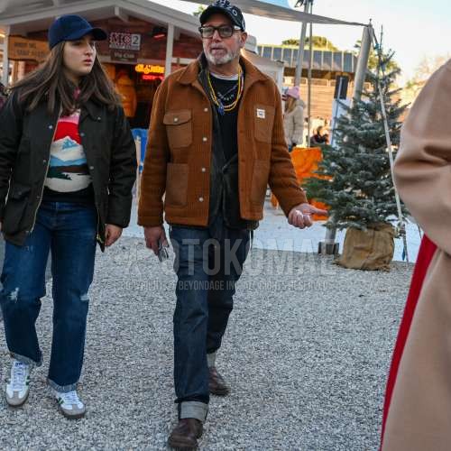 黒・グレーキャップのベースボールキャップ、黒無地のサングラス、ベージュ無地のカバーオール、黒無地のカーディガン、ネイビー無地のデニム/ジーンズ、ブラウンストレートチップの革靴を合わせた秋春のメンズコーデ・着こなし。