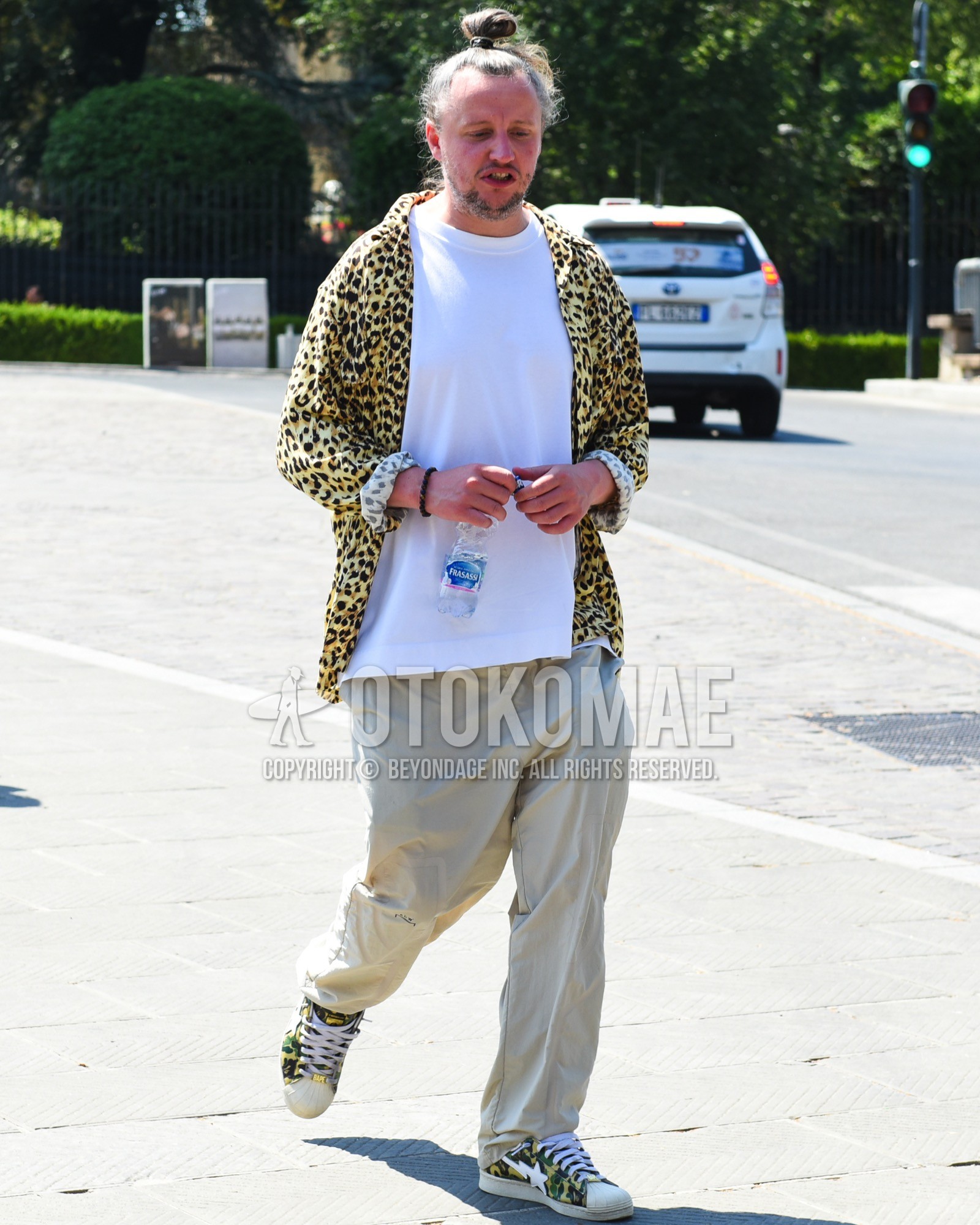 Men's spring summer outfit with yellow leopard shirt, white plain t-shirt, beige plain chinos, yellow low-cut sneakers.