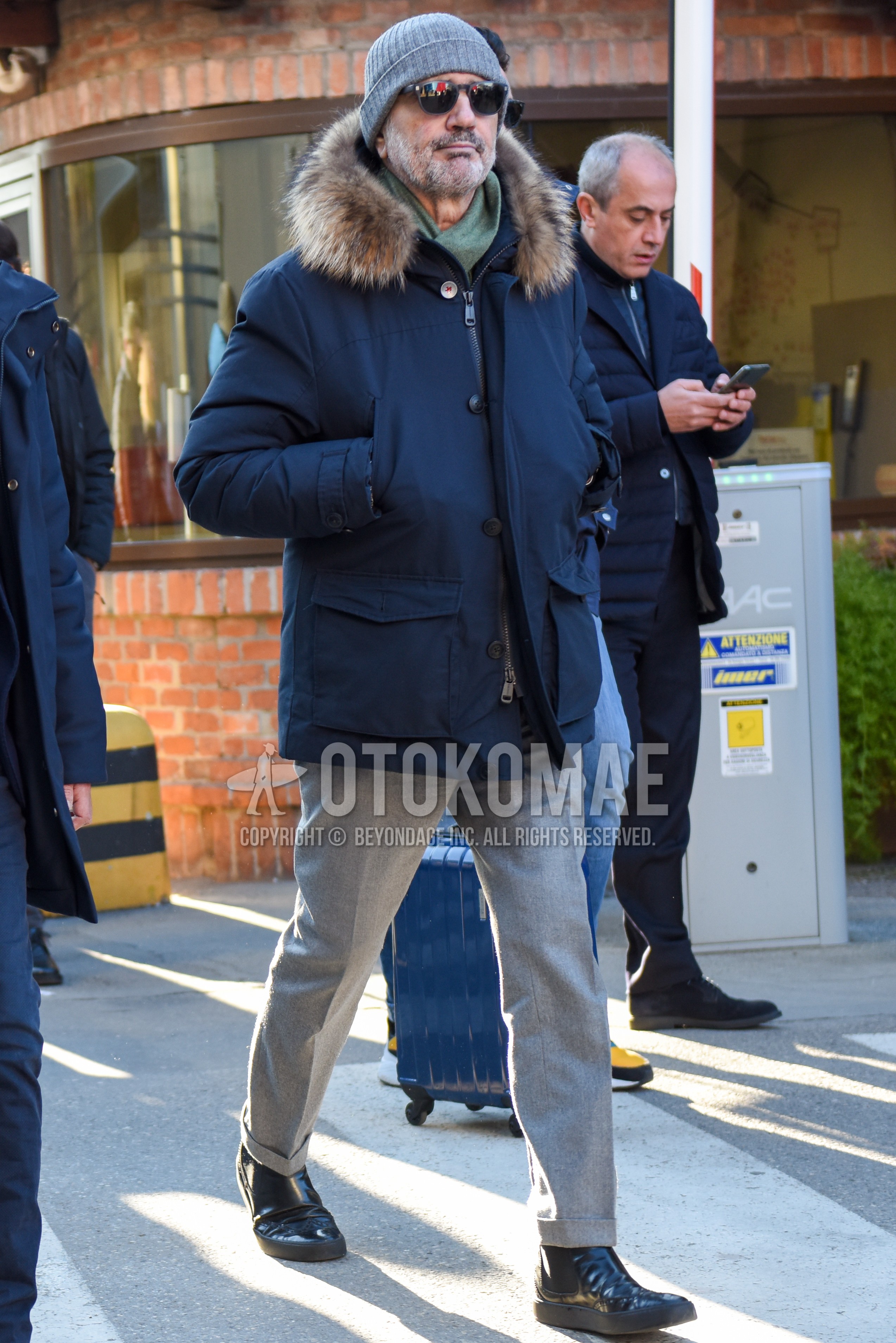 Men's winter outfit with gray plain knit cap, gray plain sunglasses, green plain scarf, navy plain down jacket, gray plain slacks, black side-gore boots.