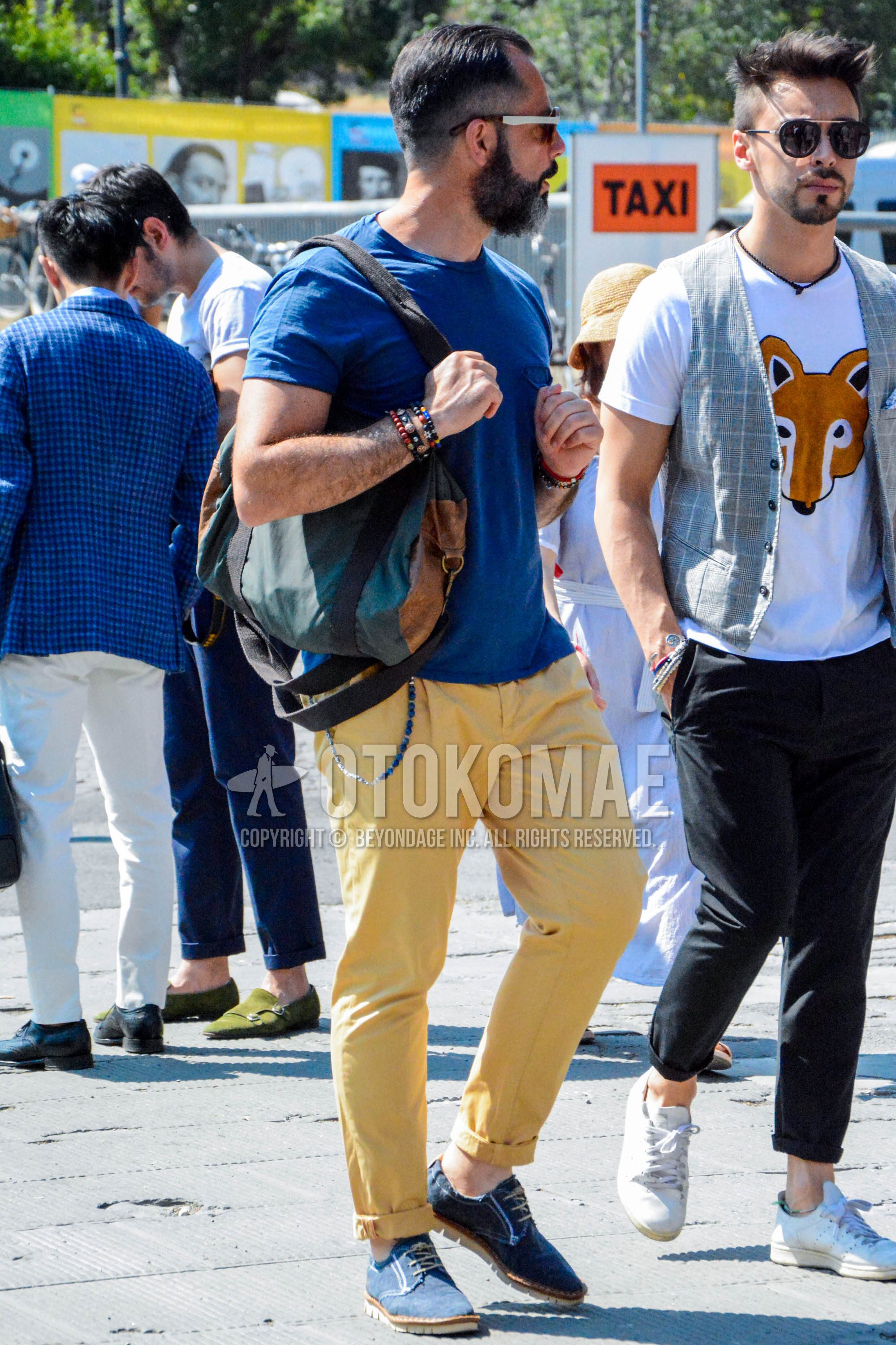 Men's spring summer outfit with brown tortoiseshell sunglasses, blue plain t-shirt, yellow plain cotton pants, navy plain toe leather shoes, gray plain shoulder bag.