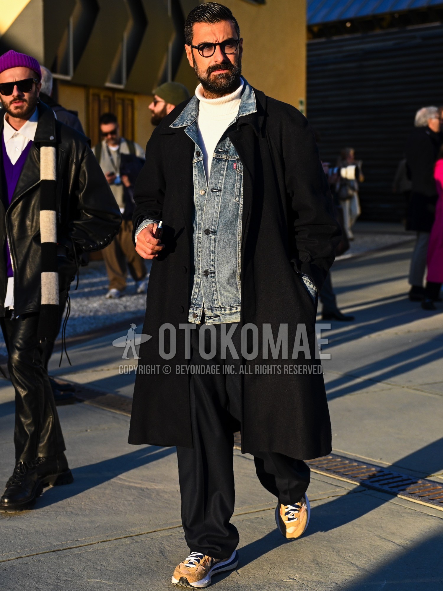 Men's autumn winter outfit with black plain glasses, blue plain denim jacket, black plain ulster coat, white plain turtleneck knit, black plain slacks, yellow low-cut sneakers.