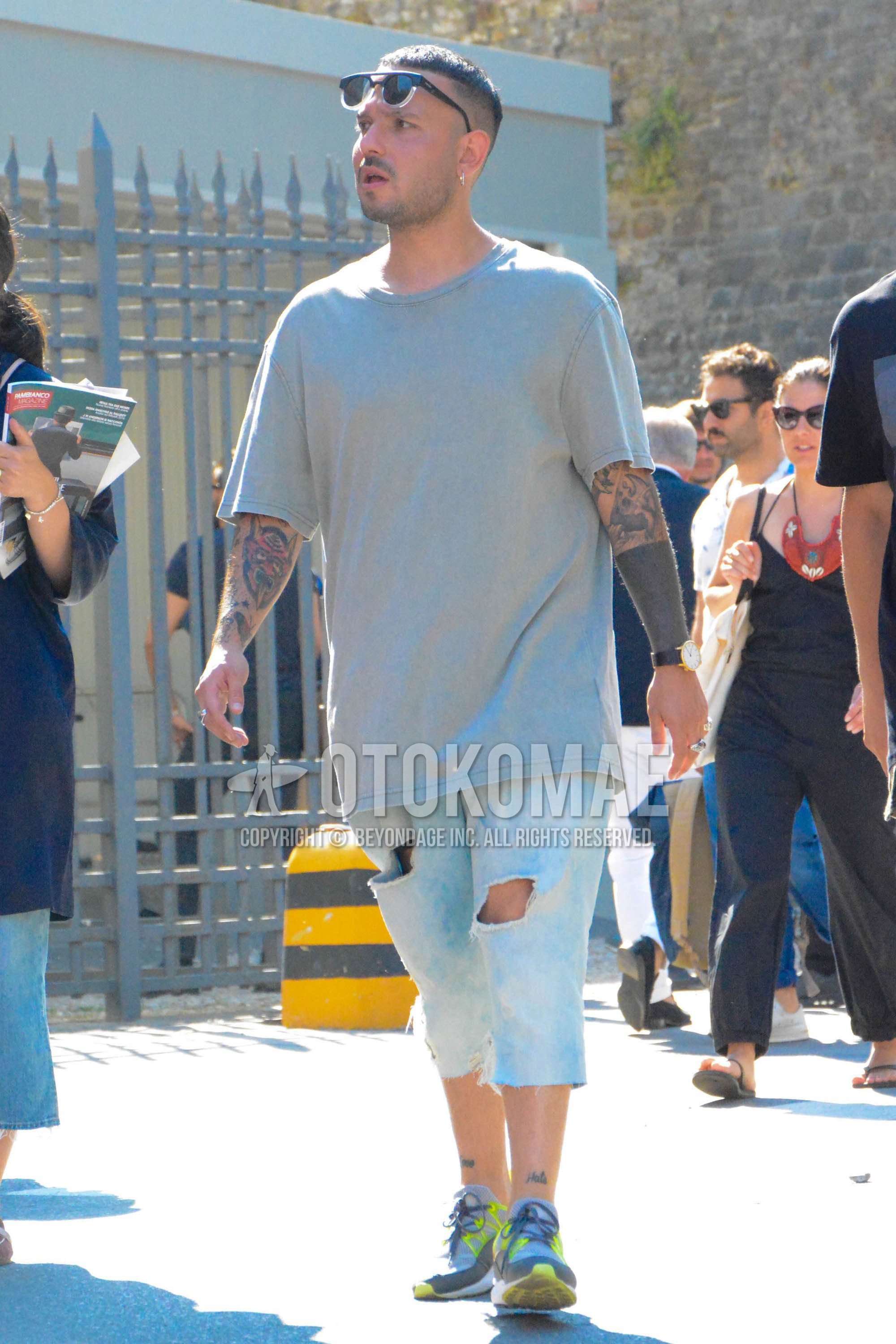Men's summer outfit with plain sunglasses, gray plain t-shirt, light blue plain denim/jeans, gray low-cut sneakers.