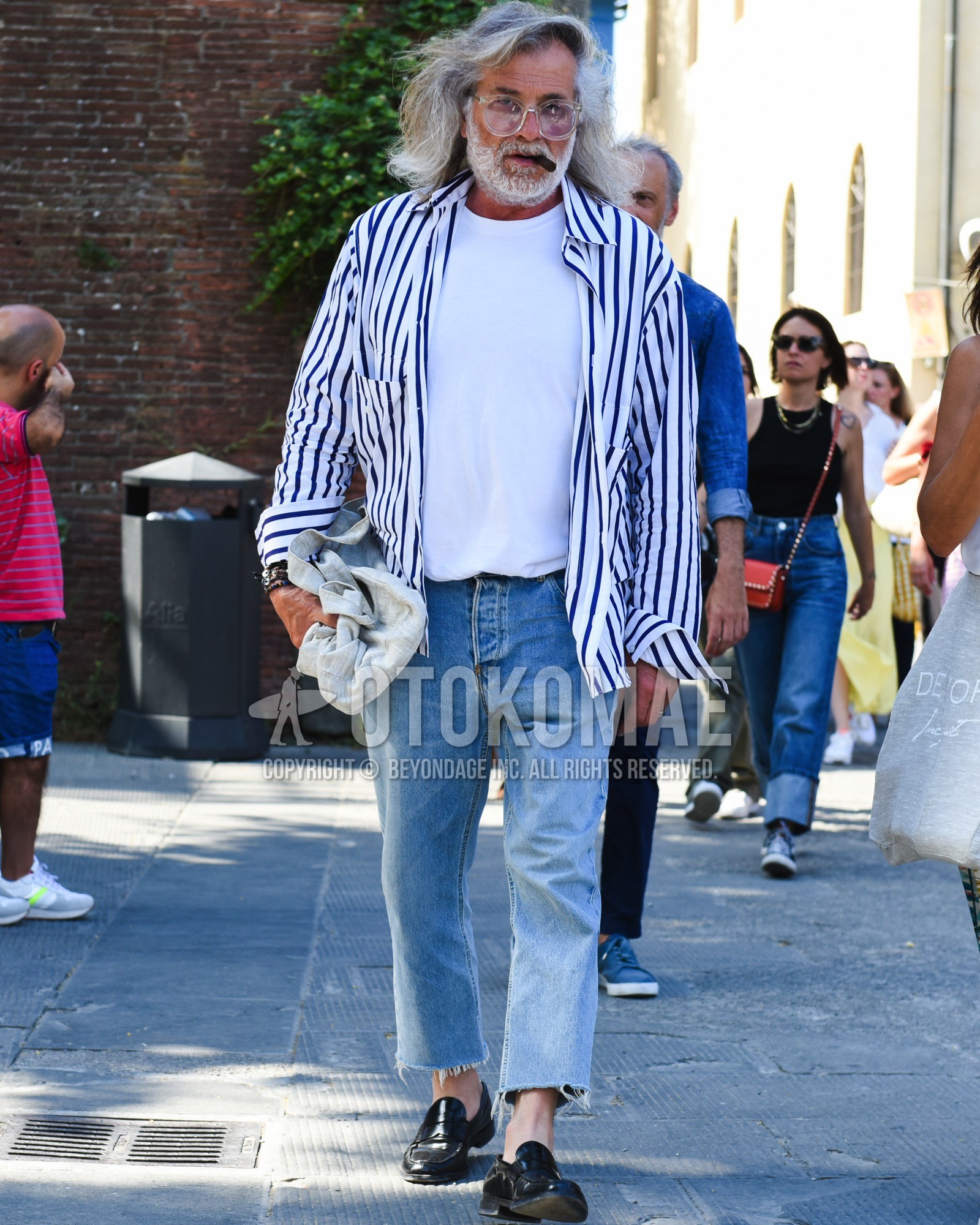 Men's spring summer outfit with clear plain glasses, purple white stripes shirt, white plain t-shirt, blue plain denim/jeans, black coin loafers leather shoes, gray plain tote bag.