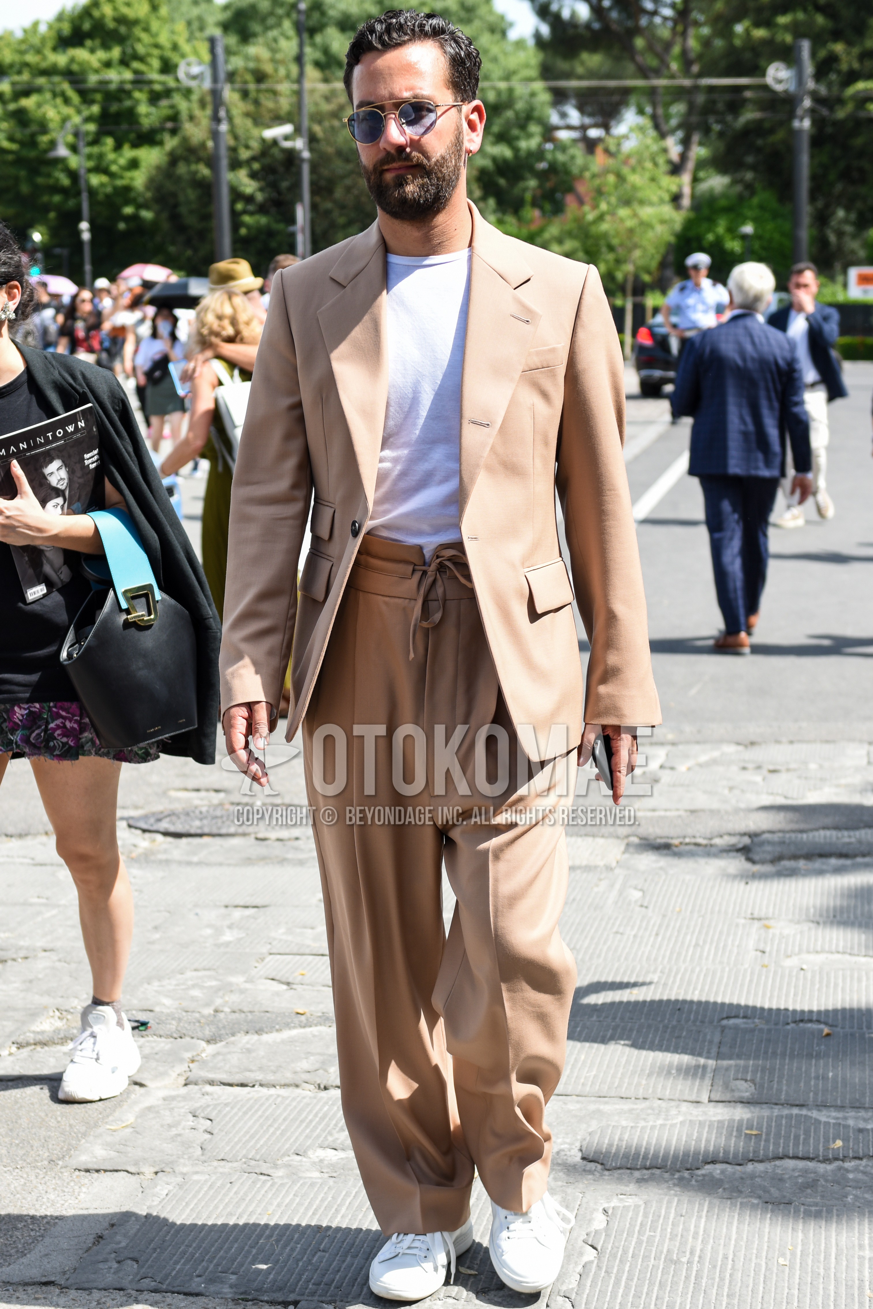 Men's spring summer autumn outfit with gold plain sunglasses, beige plain tailored jacket, white plain t-shirt, beige plain wide pants, white low-cut sneakers.