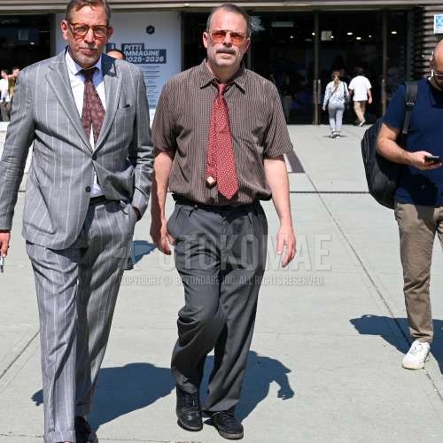 シルバー無地のサングラス、ブラウンチェックのシャツ、グレー無地のスラックス、グレー無地のプリーツパンツ、黒ローカットのスニーカー、レッドネクタイのネクタイを合わせた夏春のメンズコーデ・着こなし。