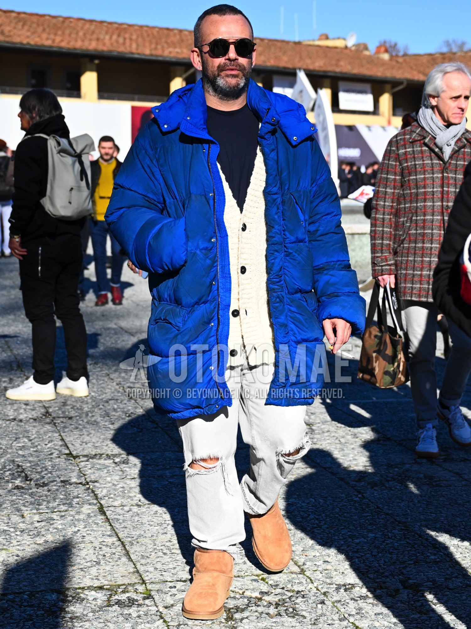 Men's autumn winter outfit with black plain sunglasses, blue plain down jacket, navy plain t-shirt, white plain cardigan, gray plain damaged jeans, gray plain denim/jeans, brown  boots.