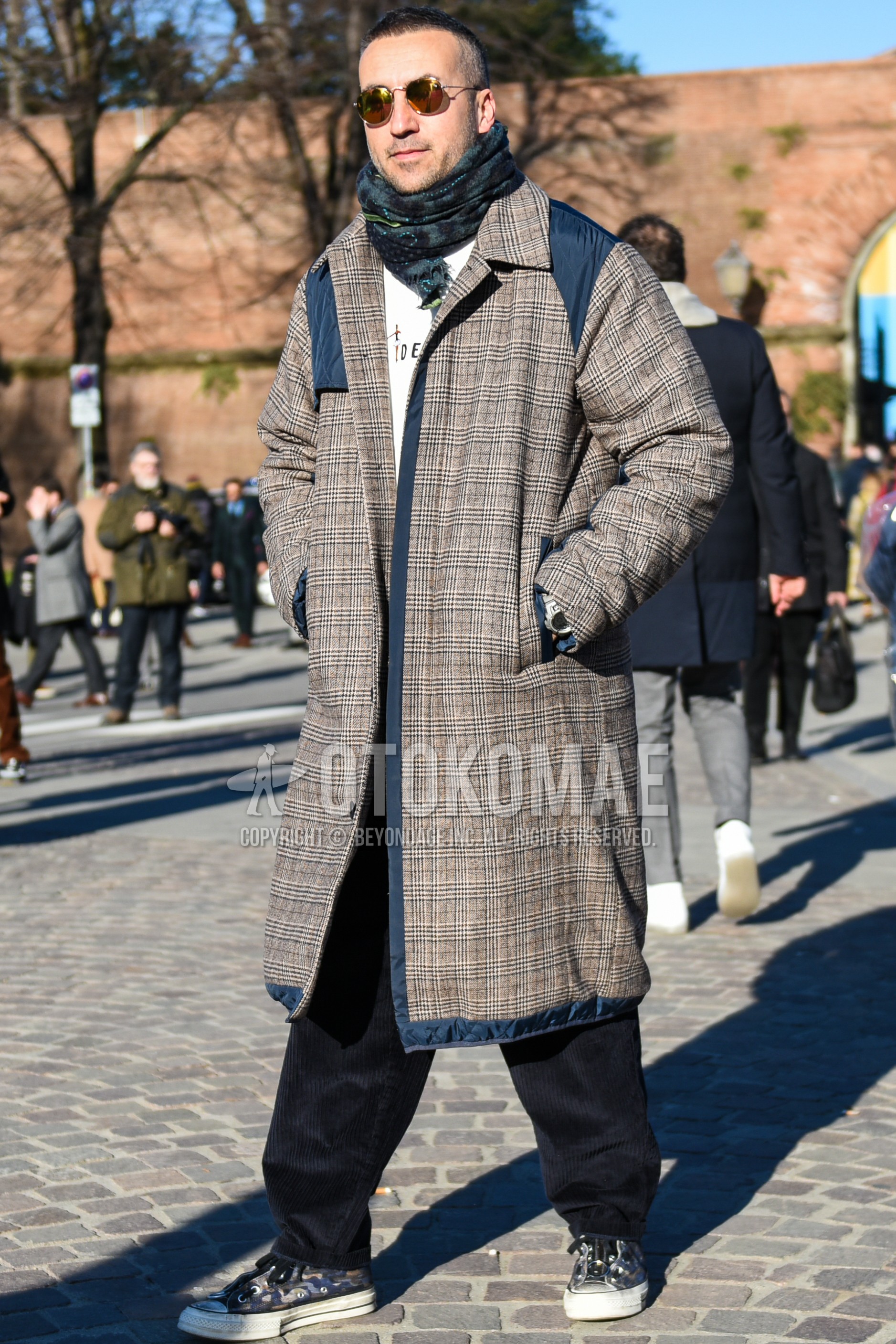 Men's autumn winter outfit with silver plain sunglasses, gray dark gray check scarf, gray check stenkarrer coat, white graphic sweatshirt, black plain winter pants (corduroy,velour), gray low-cut sneakers.