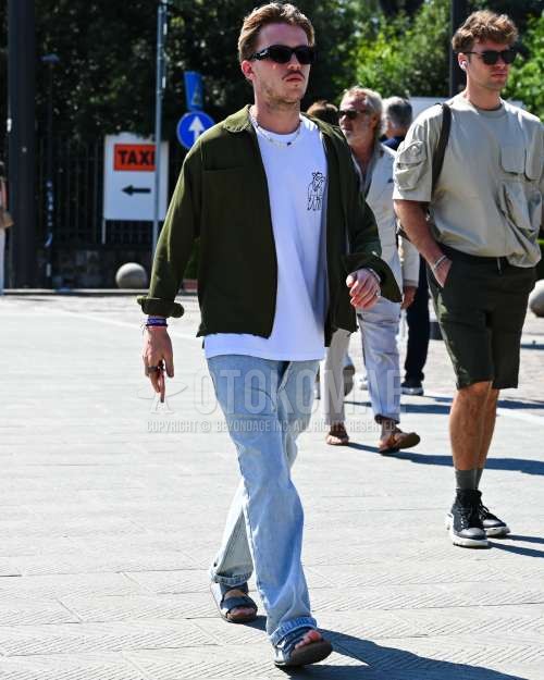 黒無地のサングラス、グリーン無地のアウター、白ワンポイントのTシャツ、水色無地のデニム/ジーンズ、ネイビースポーツサンダルを合わせた秋夏春のメンズコーデ・着こなし。