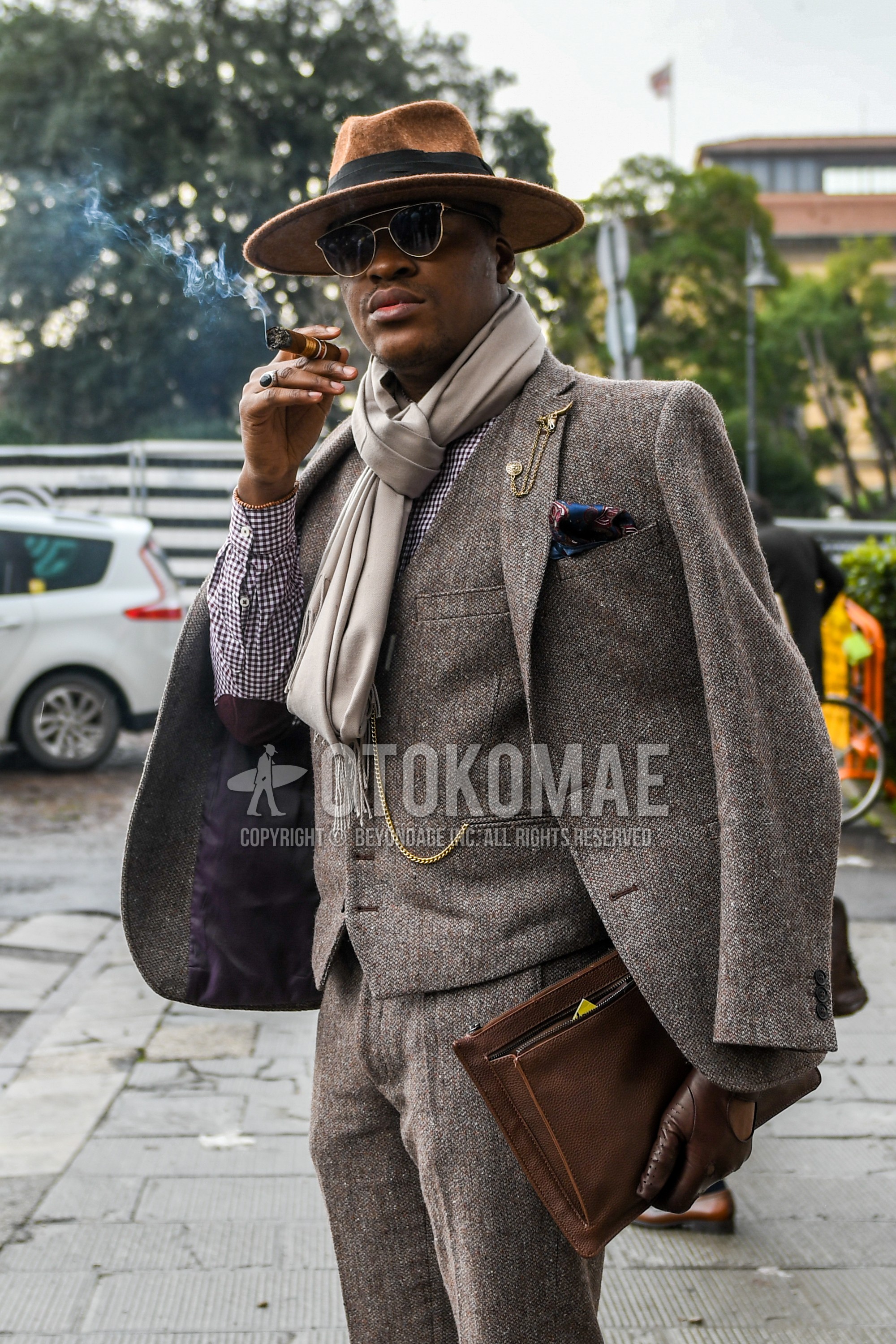Men's winter outfit with brown plain hat, plain sunglasses, brown plain scarf, purple check shirt, brown bag briefcase/handbag.