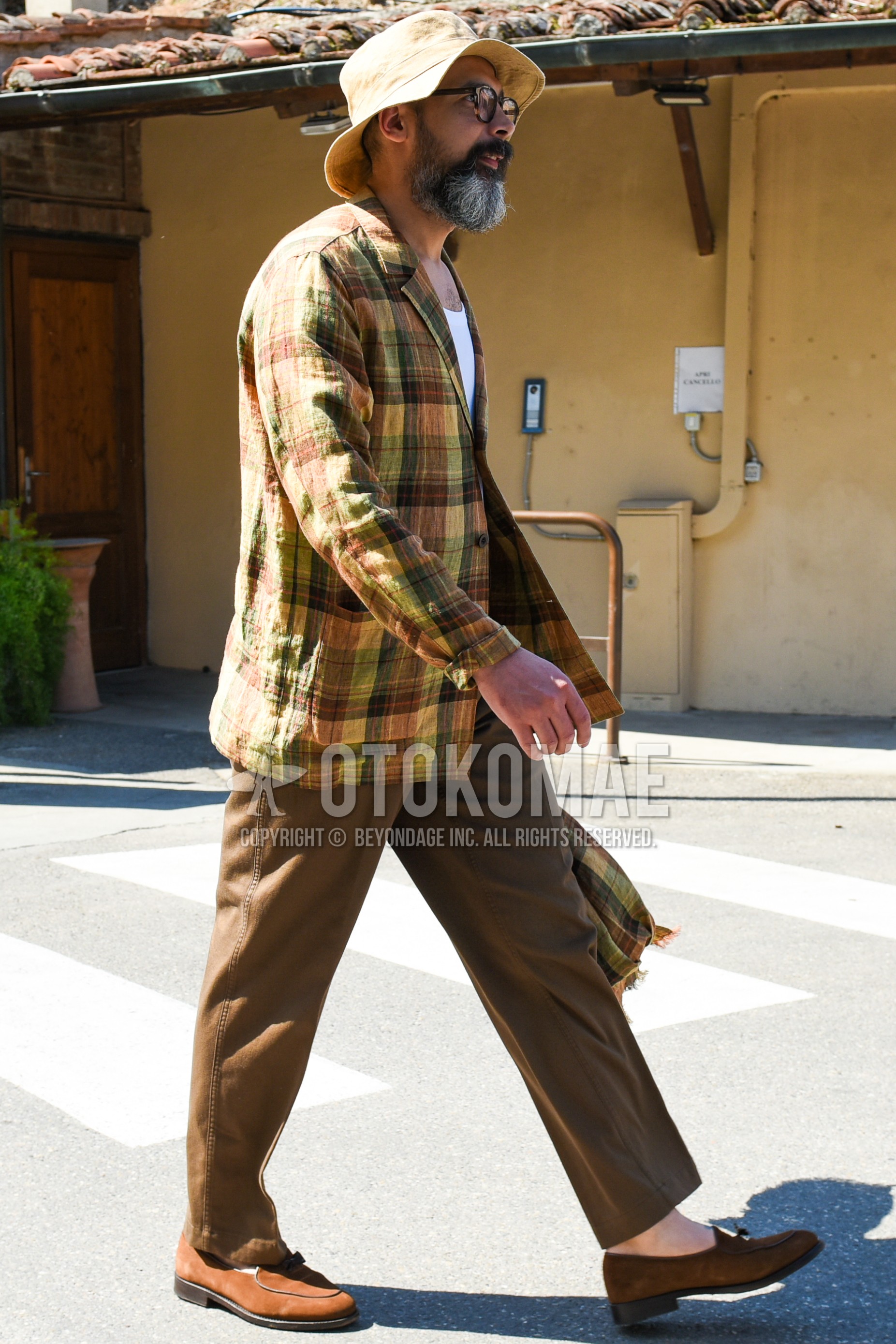 Men's spring summer autumn outfit with beige plain bucket hat, brown plain sunglasses, brown beige check tailored jacket, white plain t-shirt, brown plain chinos, brown tassel loafers leather shoes.