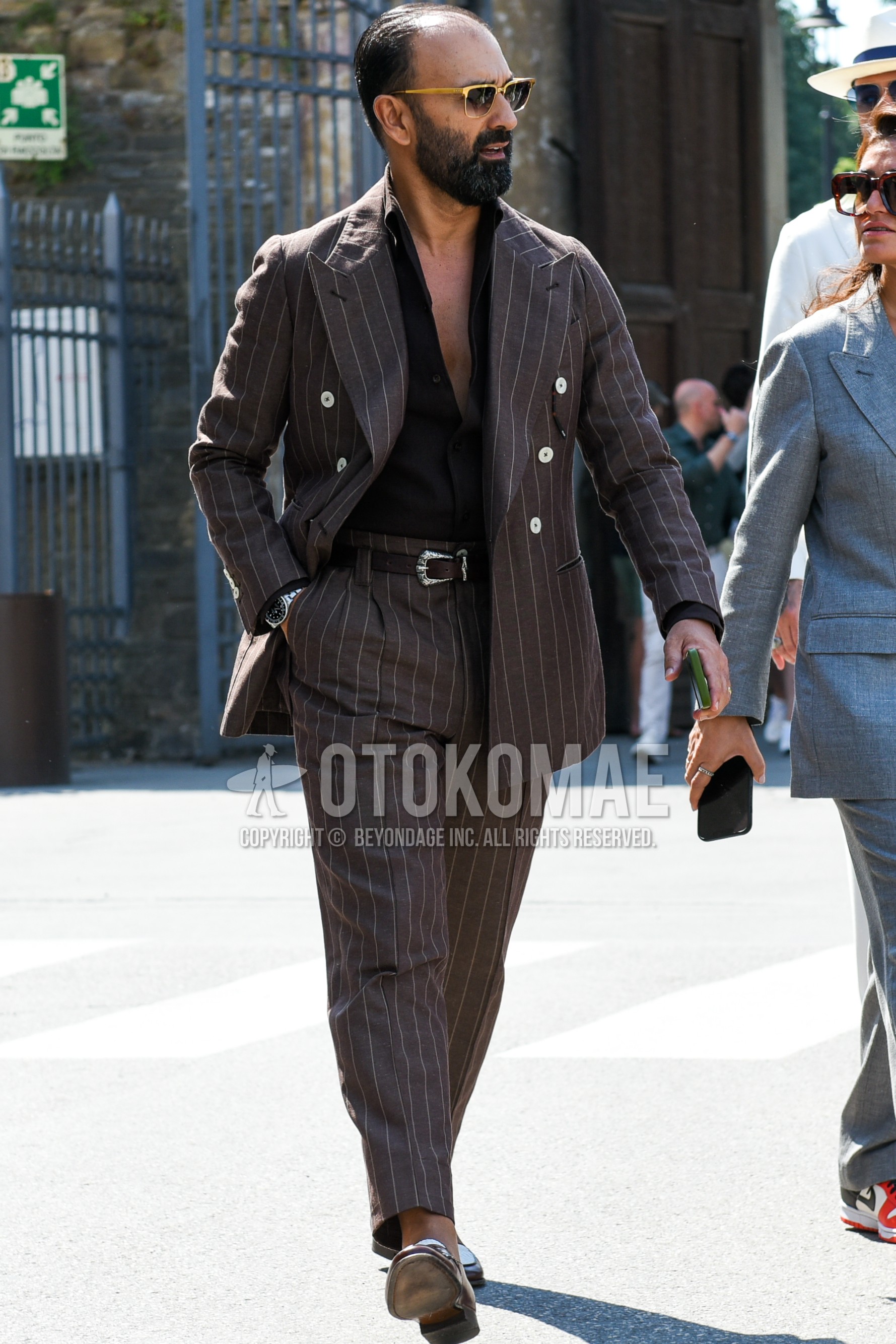 Men's spring summer autumn outfit with black plain sunglasses, brown plain shirt, brown plain leather belt, brown coin loafers leather shoes, brown stripes suit.