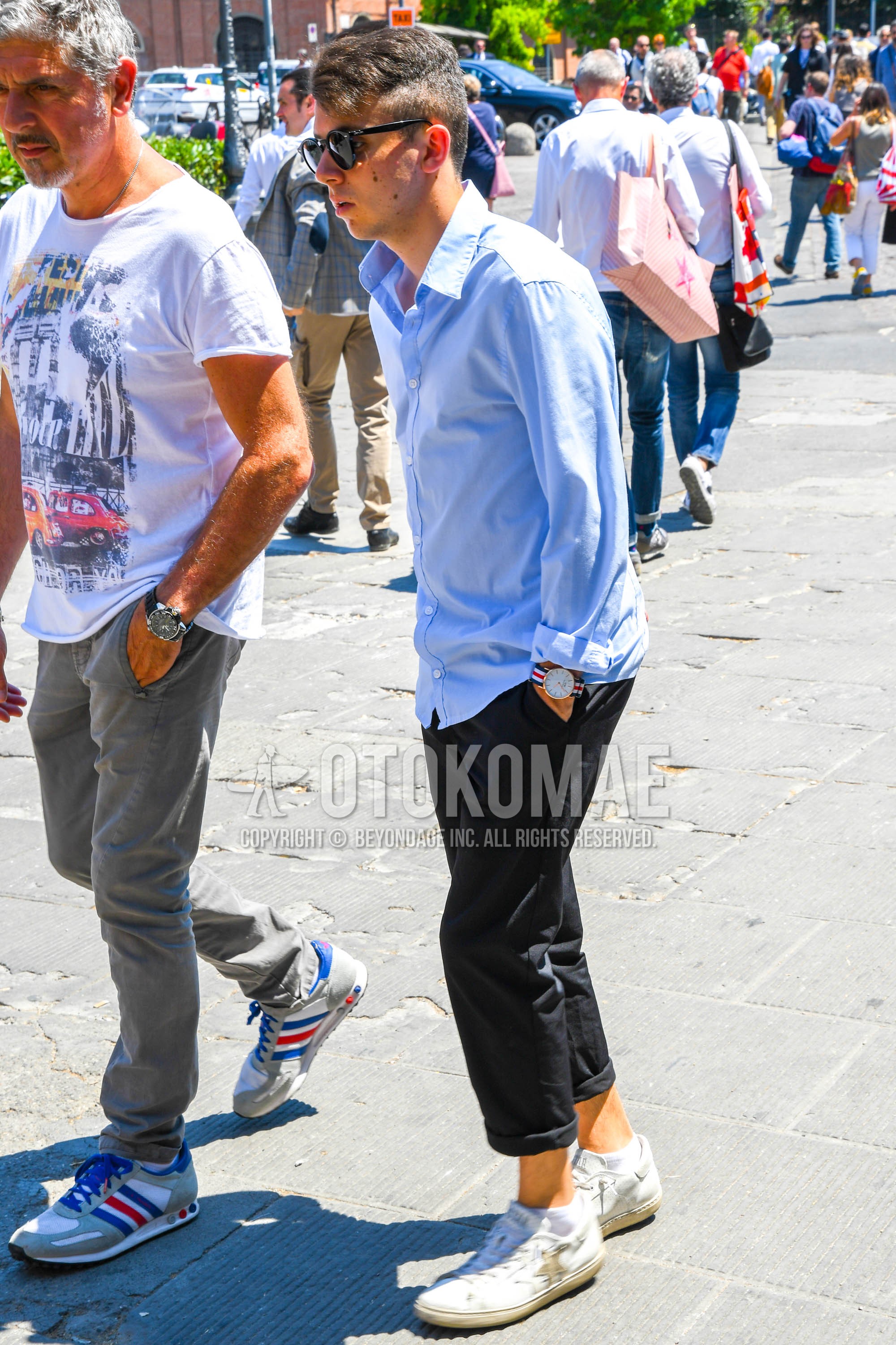 Men's spring summer outfit with plain sunglasses, light blue plain shirt, black plain cotton pants, white low-cut sneakers.