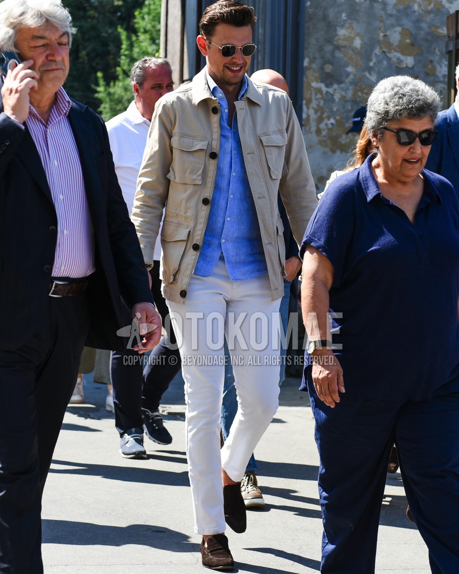 Men's spring summer outfit with gold plain sunglasses, beige plain field jacket/hunting jacket, blue plain denim shirt/chambray shirt, white plain cotton pants, white plain skinny pants, brown coin loafers leather shoes, brown suede shoes leather shoes.