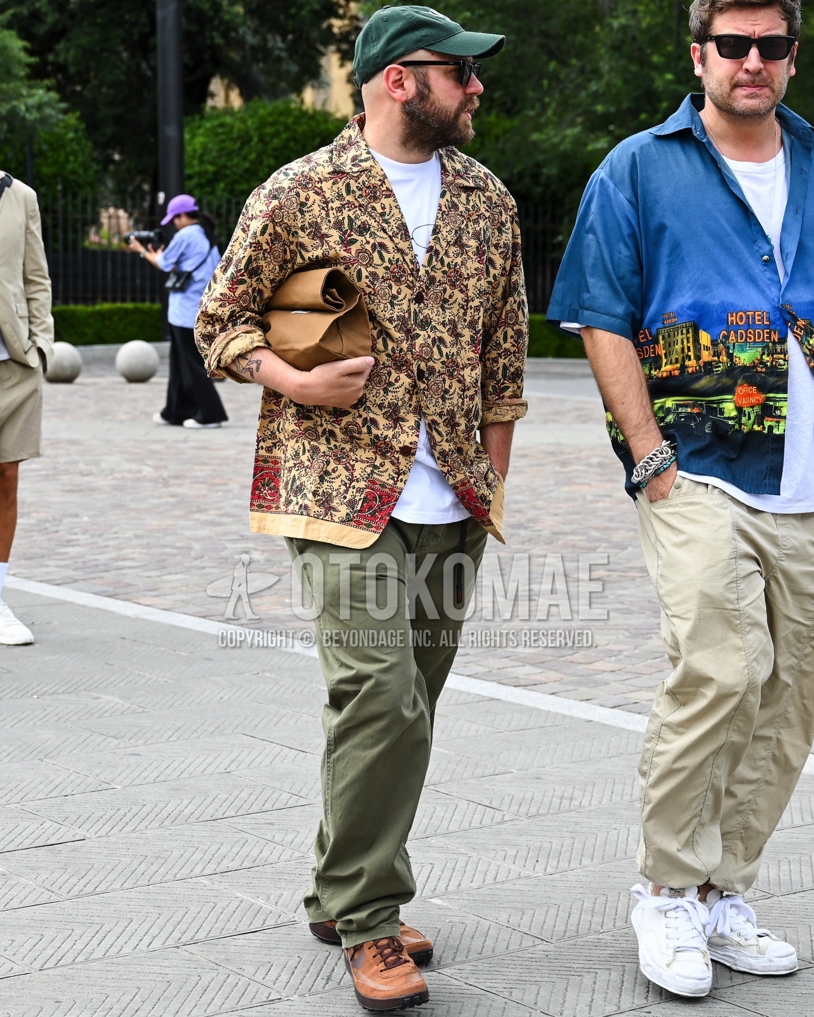 Men's spring summer autumn outfit with green one point baseball cap, black plain sunglasses, beige whole pattern shirt, olive green plain cotton pants, brown low-cut sneakers, brown plain clutch bag/second bag/drawstring bag.
