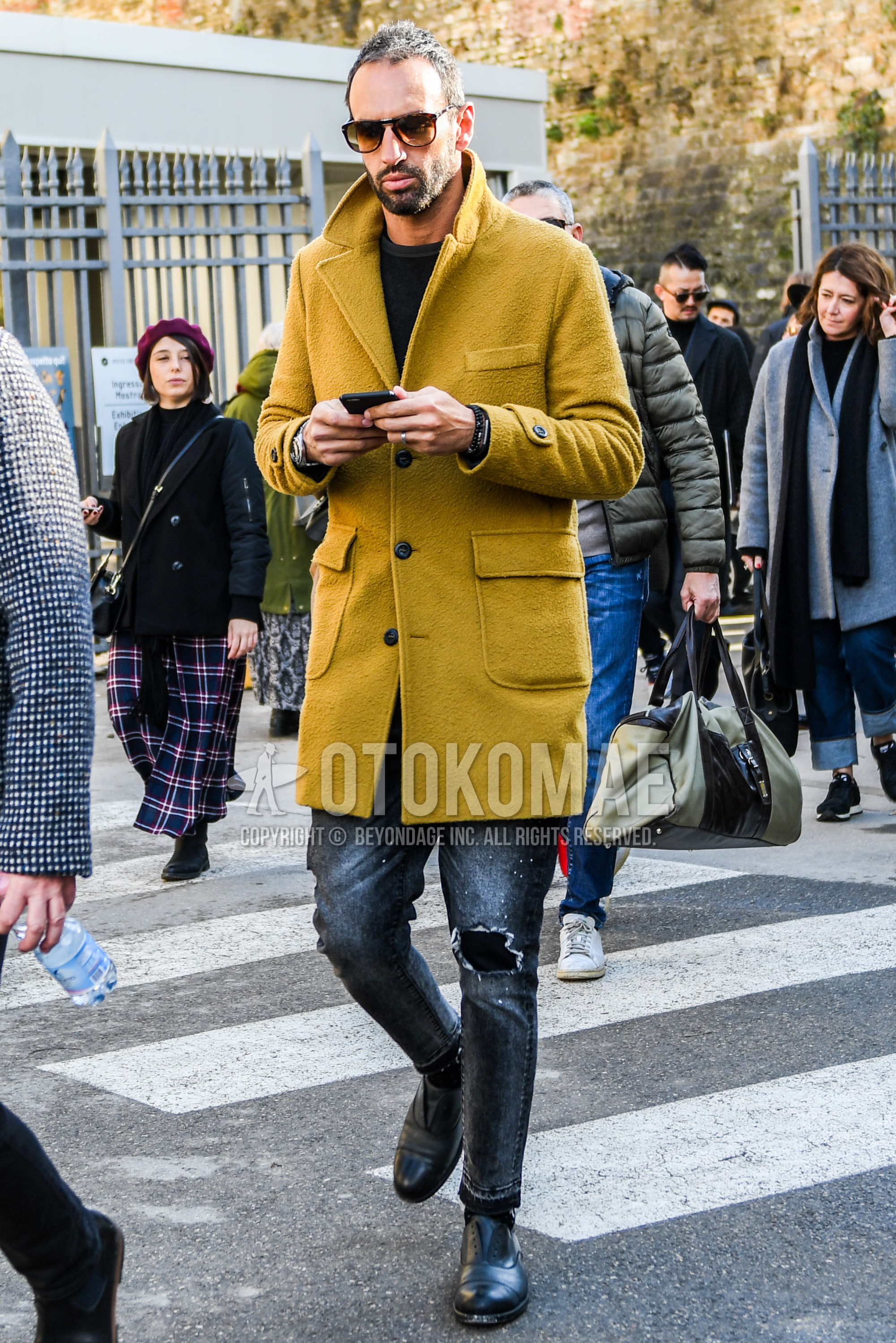 Men's autumn winter outfit with plain sunglasses, beige plain chester coat, black plain sweatshirt, gray plain damaged jeans, black plain socks, black straight-tip shoes leather shoes.