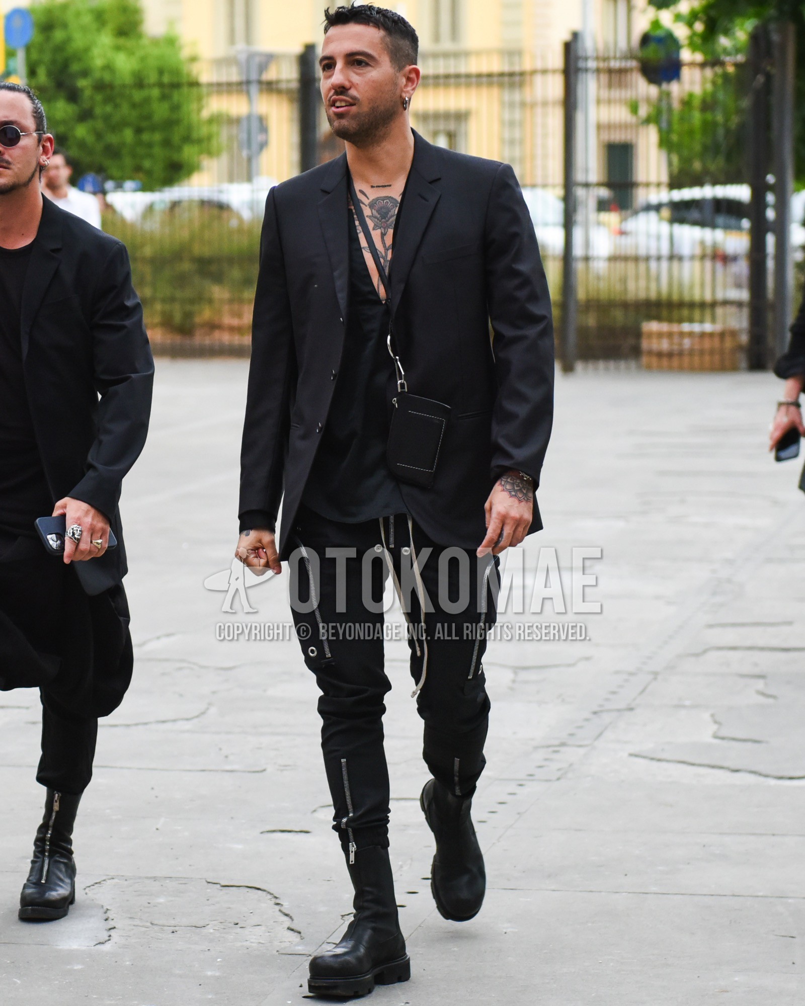 Men's spring summer outfit with black plain tailored jacket, black plain shirt, black plain easy pants, black plain cargo pants, black side-gore boots.