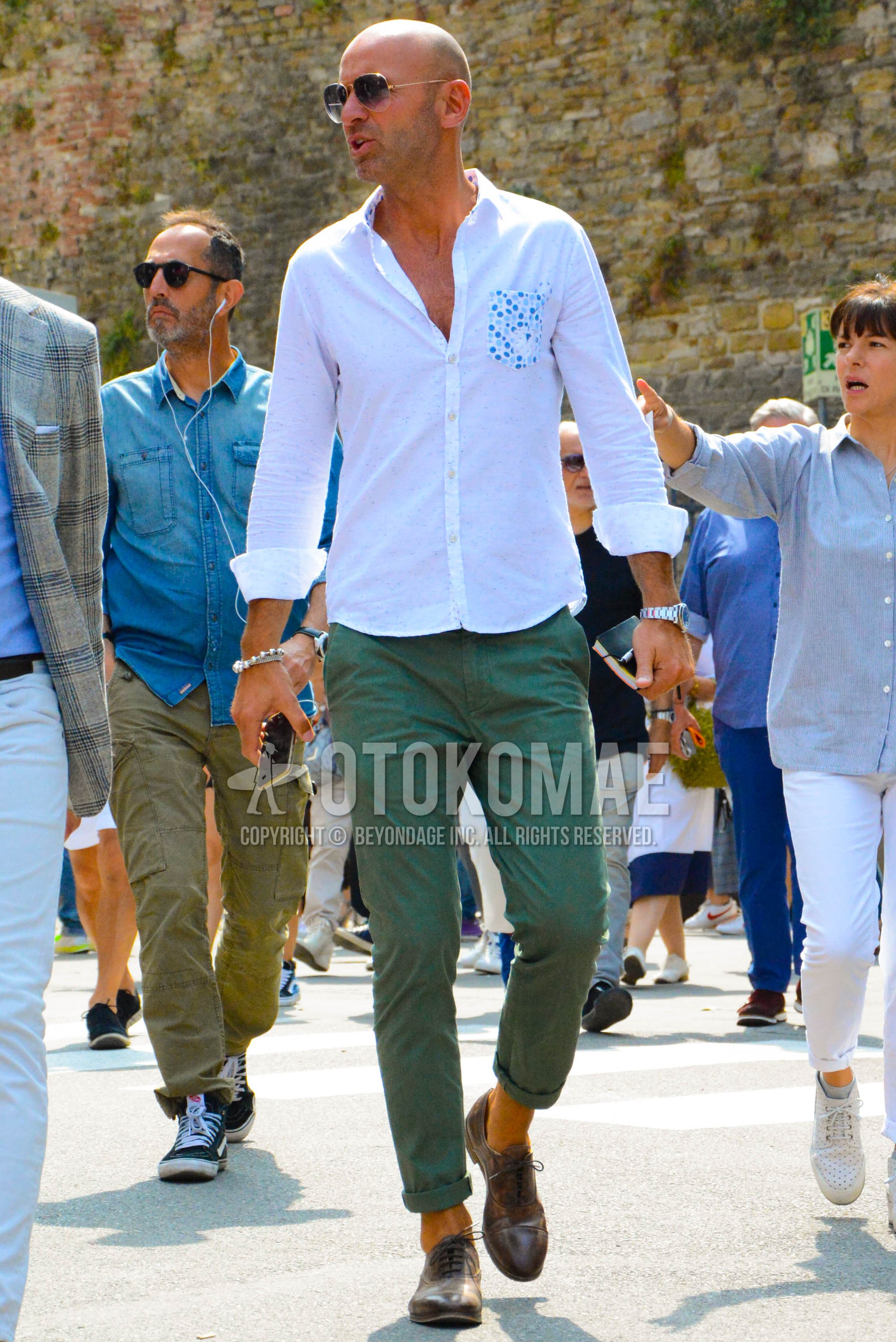 Men's spring summer outfit with gold plain sunglasses, white plain shirt, olive green plain chinos, brown straight-tip shoes leather shoes.