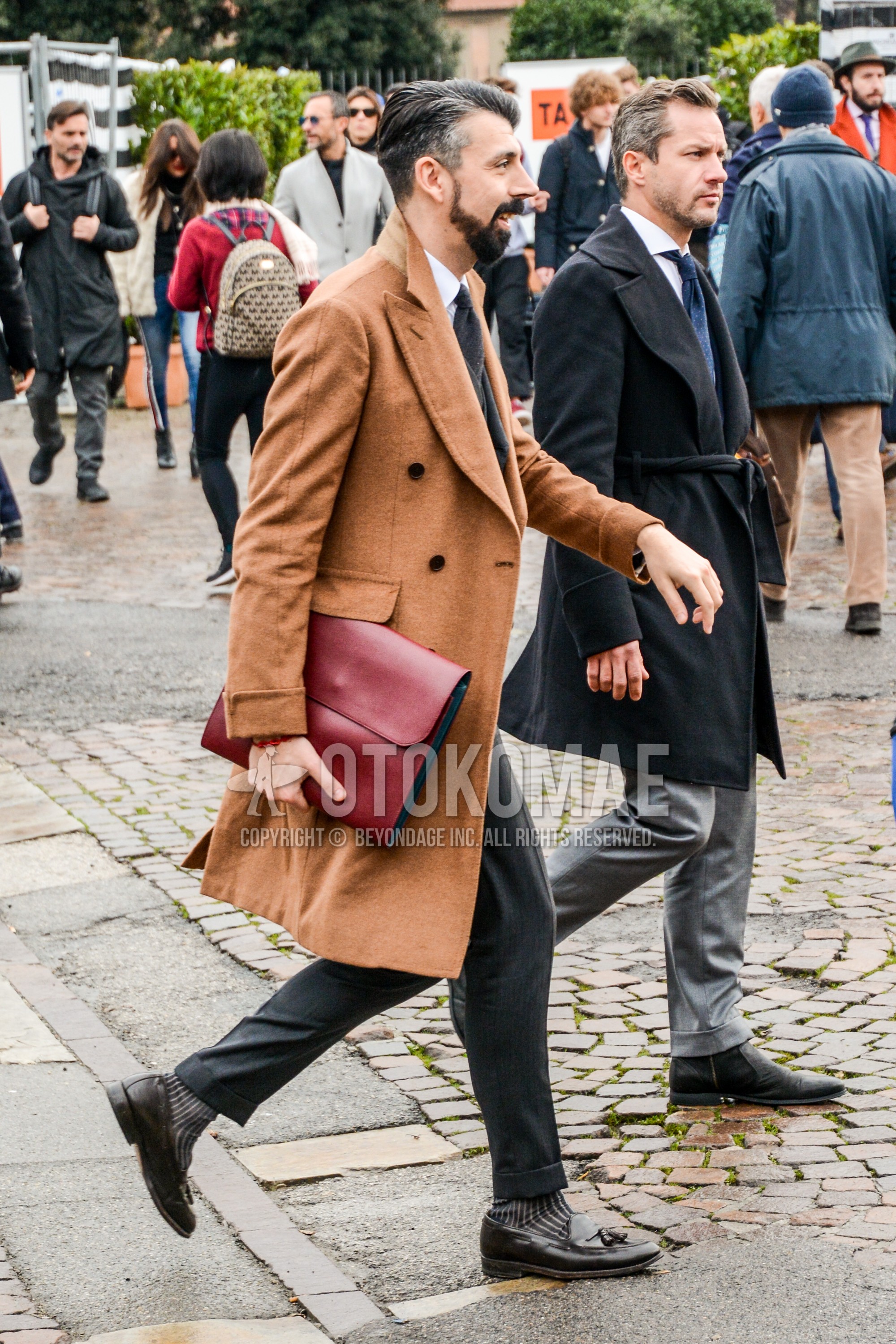 Men's autumn winter outfit with beige plain chester coat, brown stripes socks, brown tassel loafers leather shoes, red plain clutch bag/second bag/drawstring bag, gray plain suit.