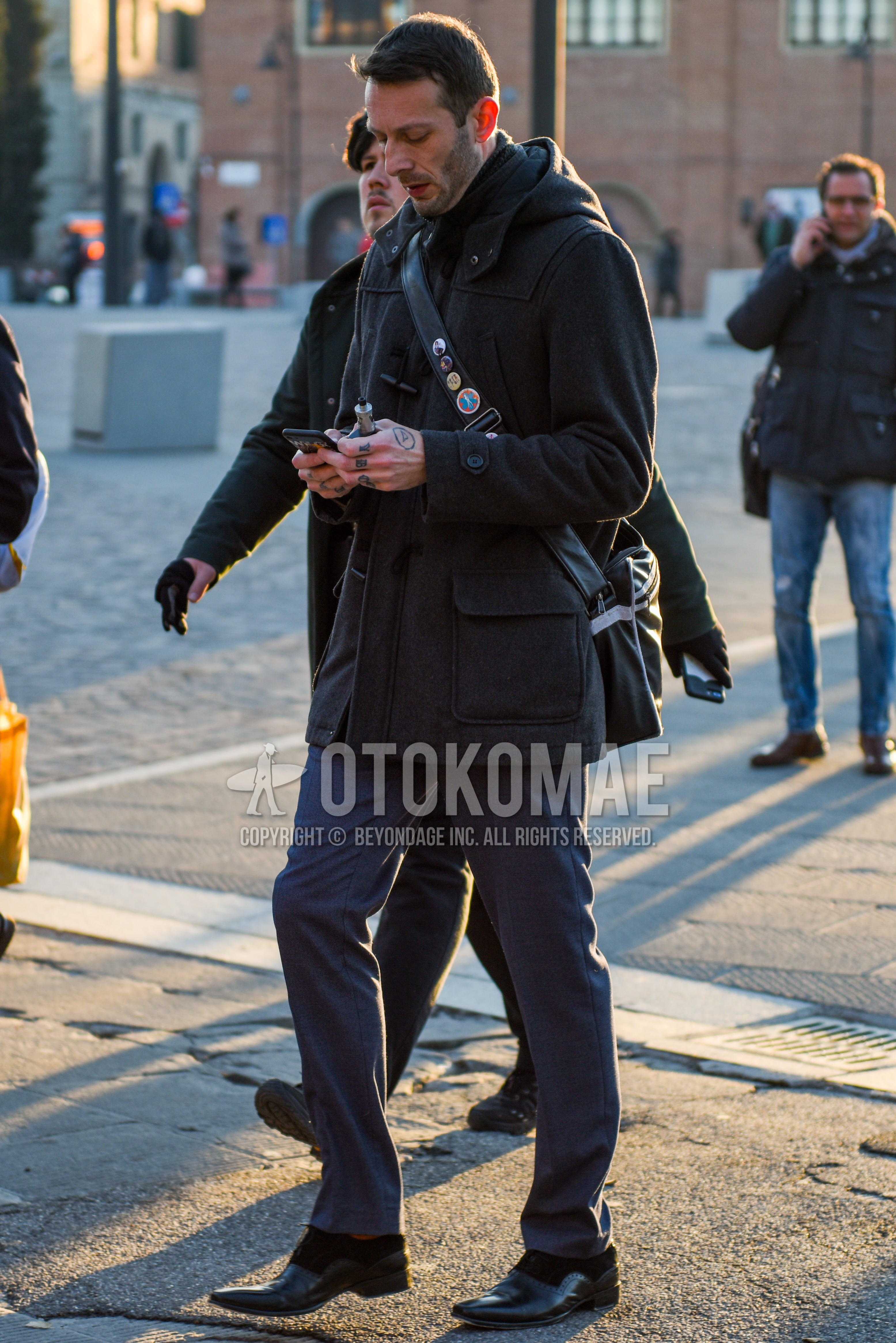 Men's autumn winter outfit with dark gray plain duffle coat, gray plain slacks, black  leather shoes, black plain shoulder bag.