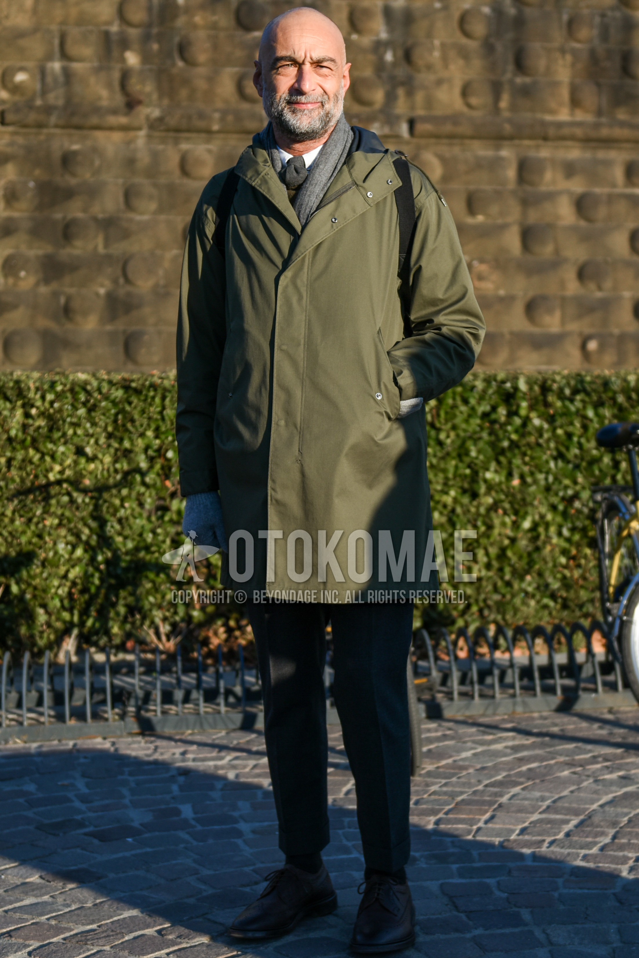 Men's autumn winter outfit with gray plain scarf, olive green plain hooded coat, white plain shirt, gray plain slacks, gray plain ankle pants, black wing-tip shoes leather shoes, gray plain necktie.