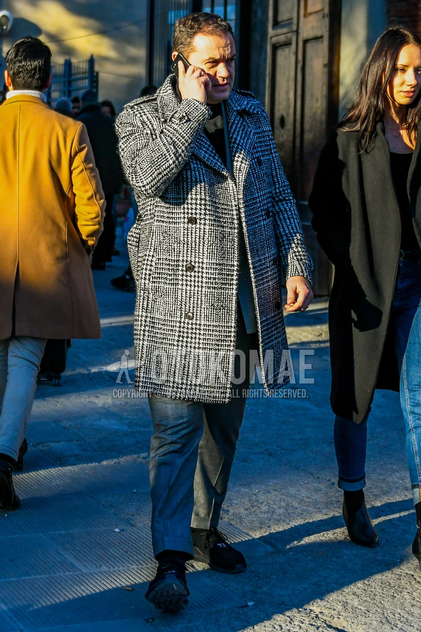 Men's winter outfit with gray check chester coat, dark gray plain slacks, black low-cut sneakers.