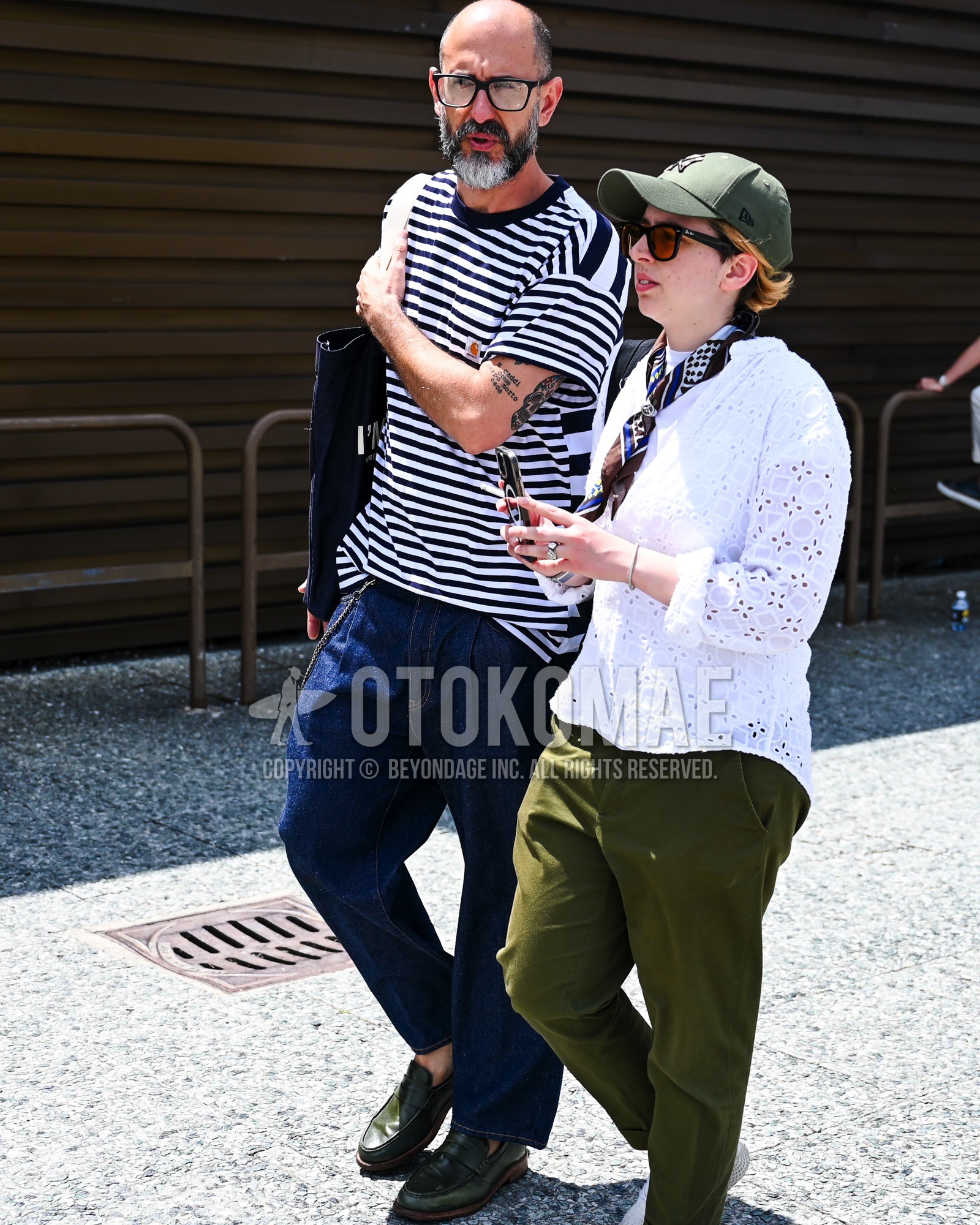 Men's spring summer outfit with clear plain sunglasses, white navy horizontal stripes t-shirt, blue plain denim/jeans, black coin loafers leather shoes, black plain tote bag.