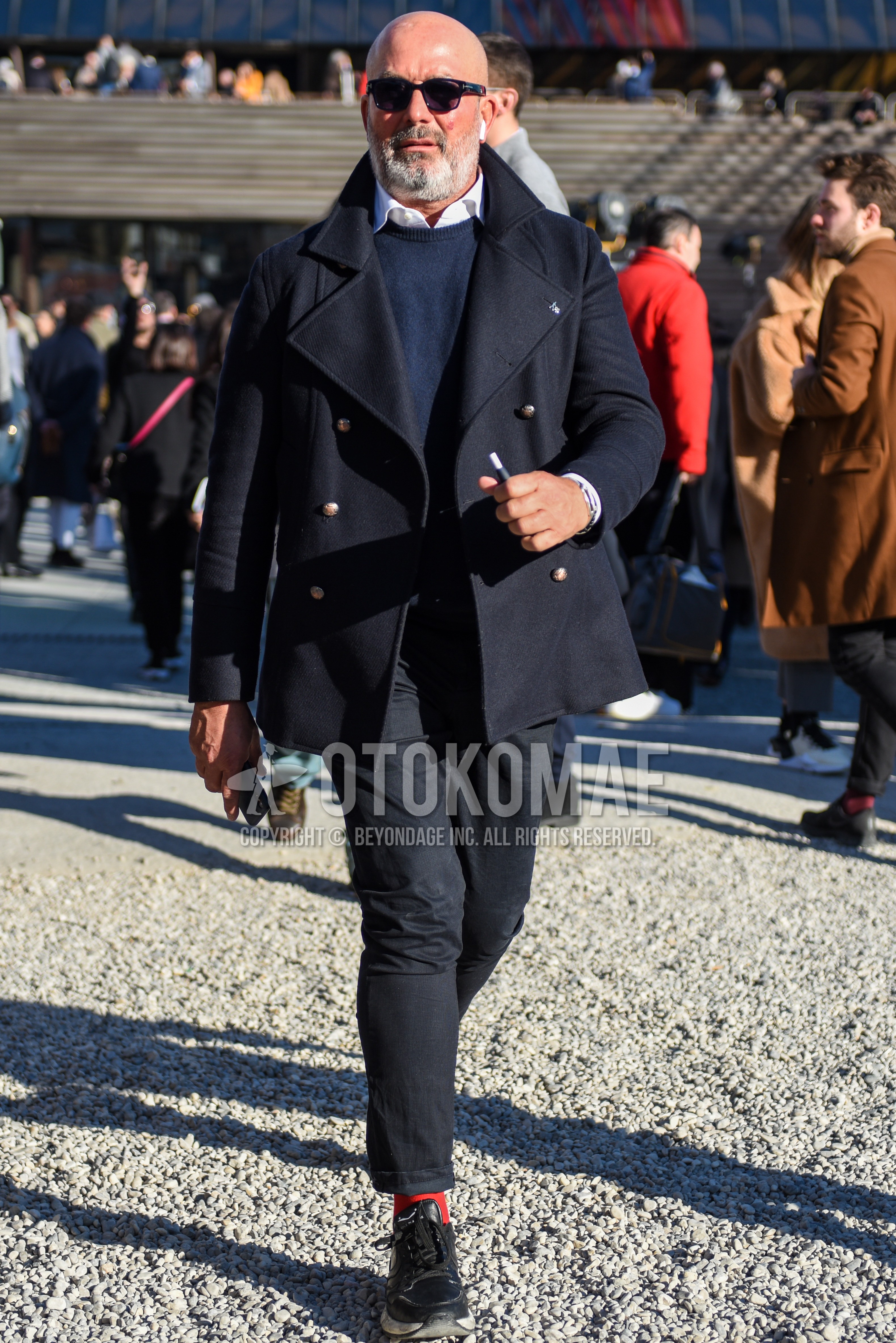 Men's autumn winter outfit with black plain sunglasses, black plain p coat, navy plain sweater, white plain shirt, dark gray plain cotton pants, red plain socks, black low-cut sneakers.