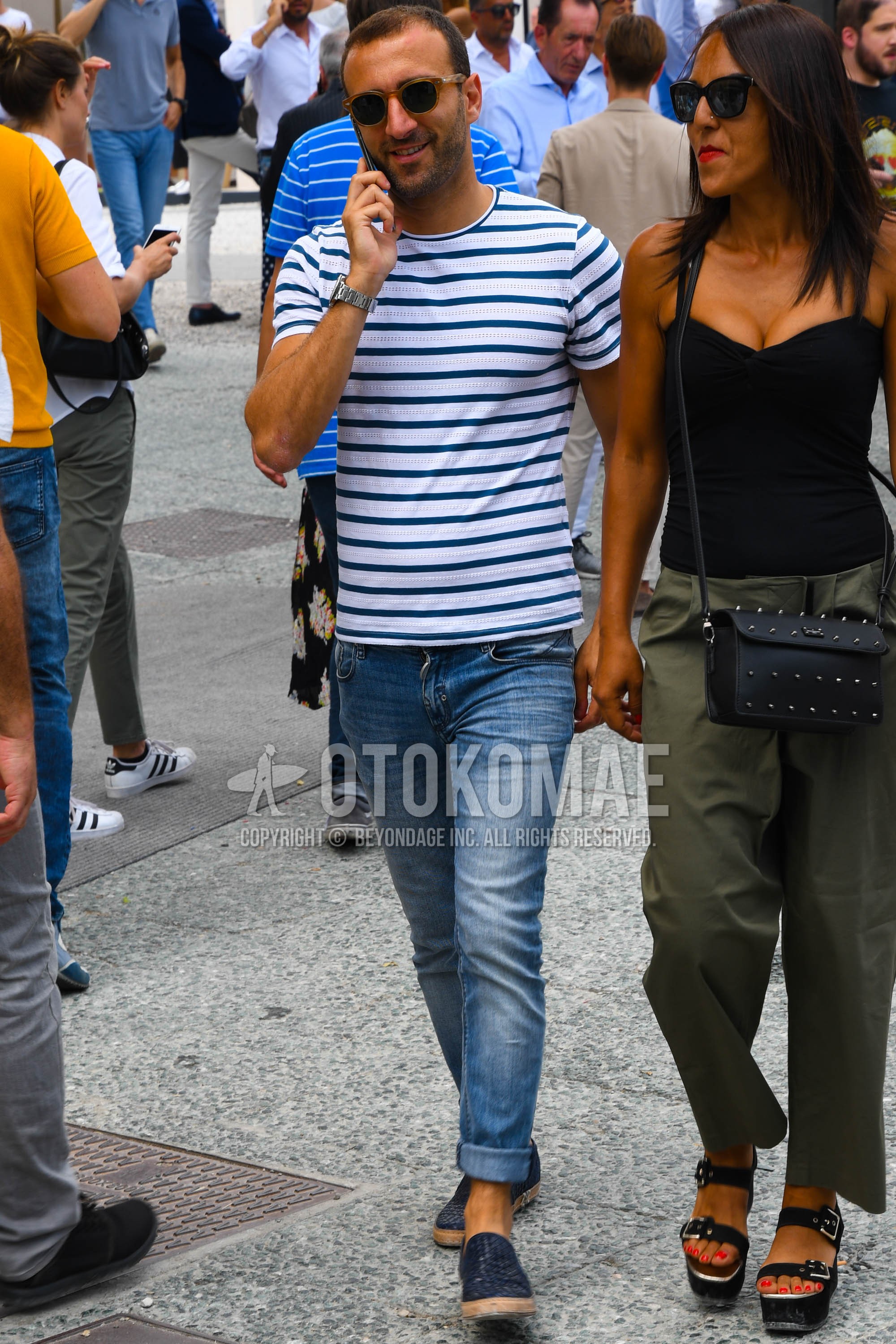 Men's summer outfit with plain sunglasses, white navy horizontal stripes t-shirt, blue plain denim/jeans, navy slip-on sneakers.