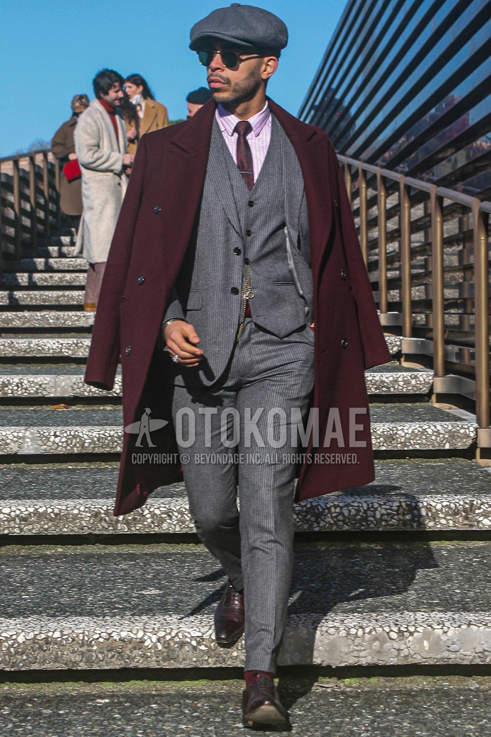 Men's spring winter outfit with gray plain hunting cap, brown plain sunglasses, red plain ulster coat, pink stripes shirt, brown brogue shoes leather shoes, gray stripes three-piece suit, red necktie necktie.