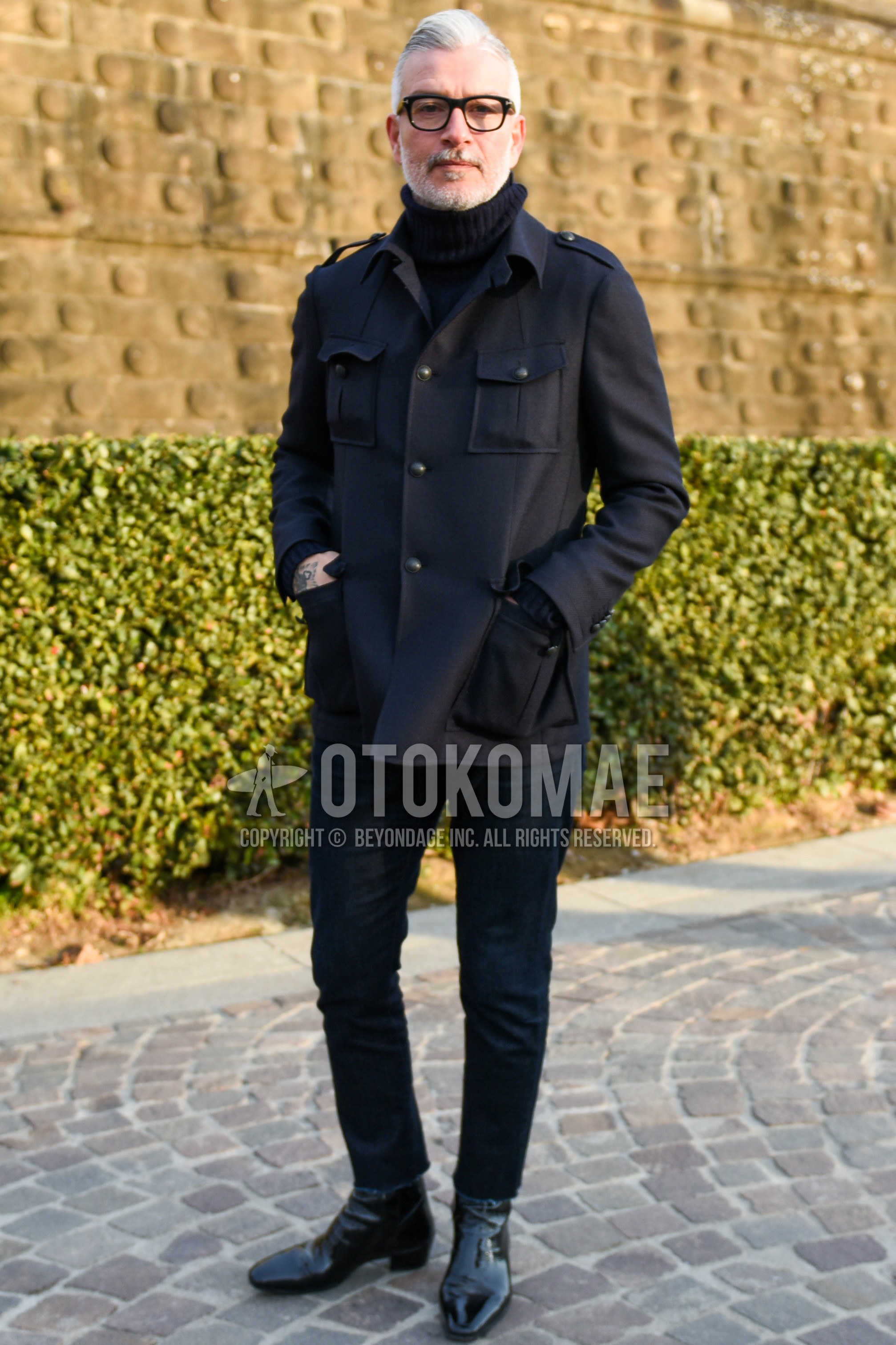 Men's autumn winter outfit with black plain glasses, dark gray plain field jacket/hunting jacket, black plain turtleneck knit, black plain denim/jeans, black plain cropped pants, black  boots.