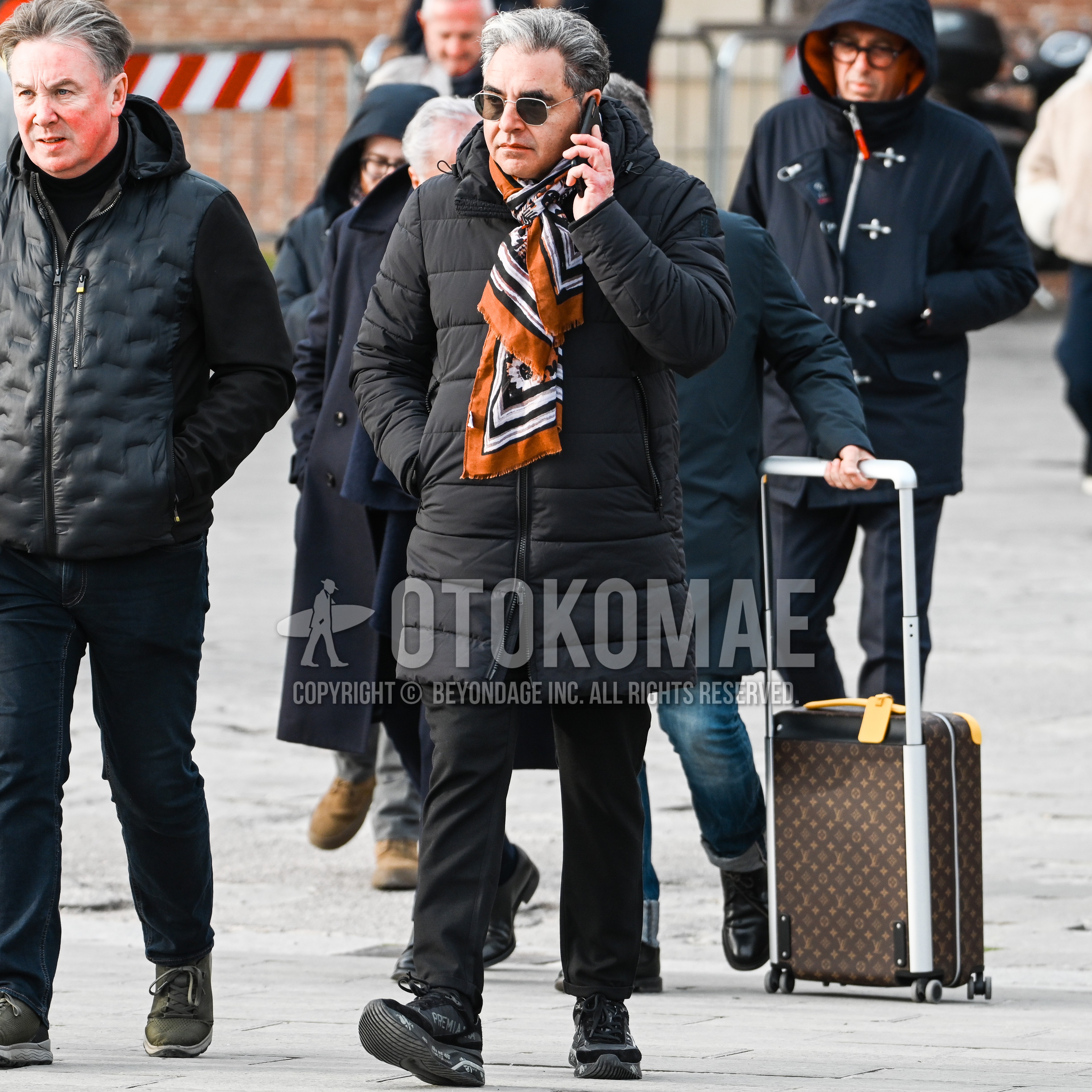 Men's autumn winter outfit with silver plain sunglasses, orange whole pattern scarf, black plain down jacket, black plain chinos, black low-cut sneakers.