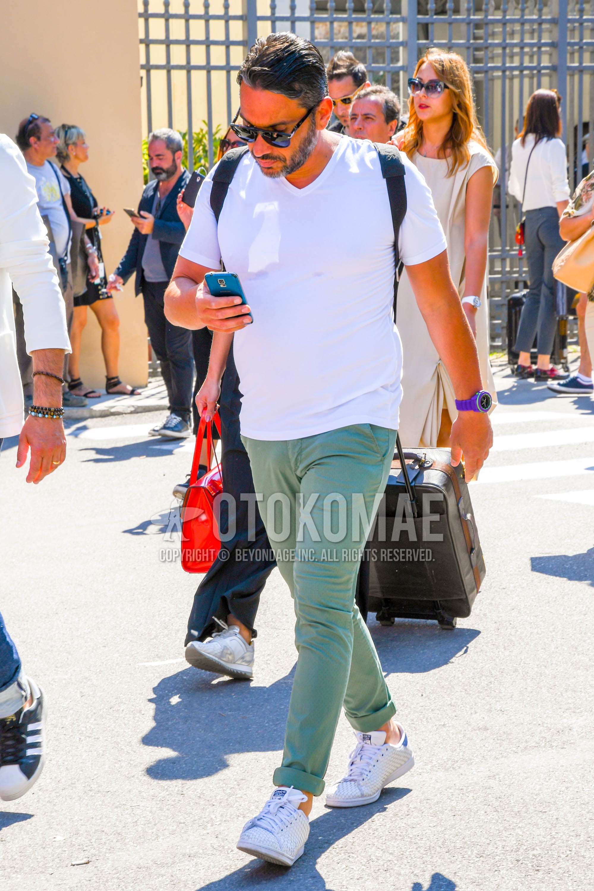 Men's summer outfit with plain sunglasses, white plain shirt, green plain chinos, white low-cut sneakers.