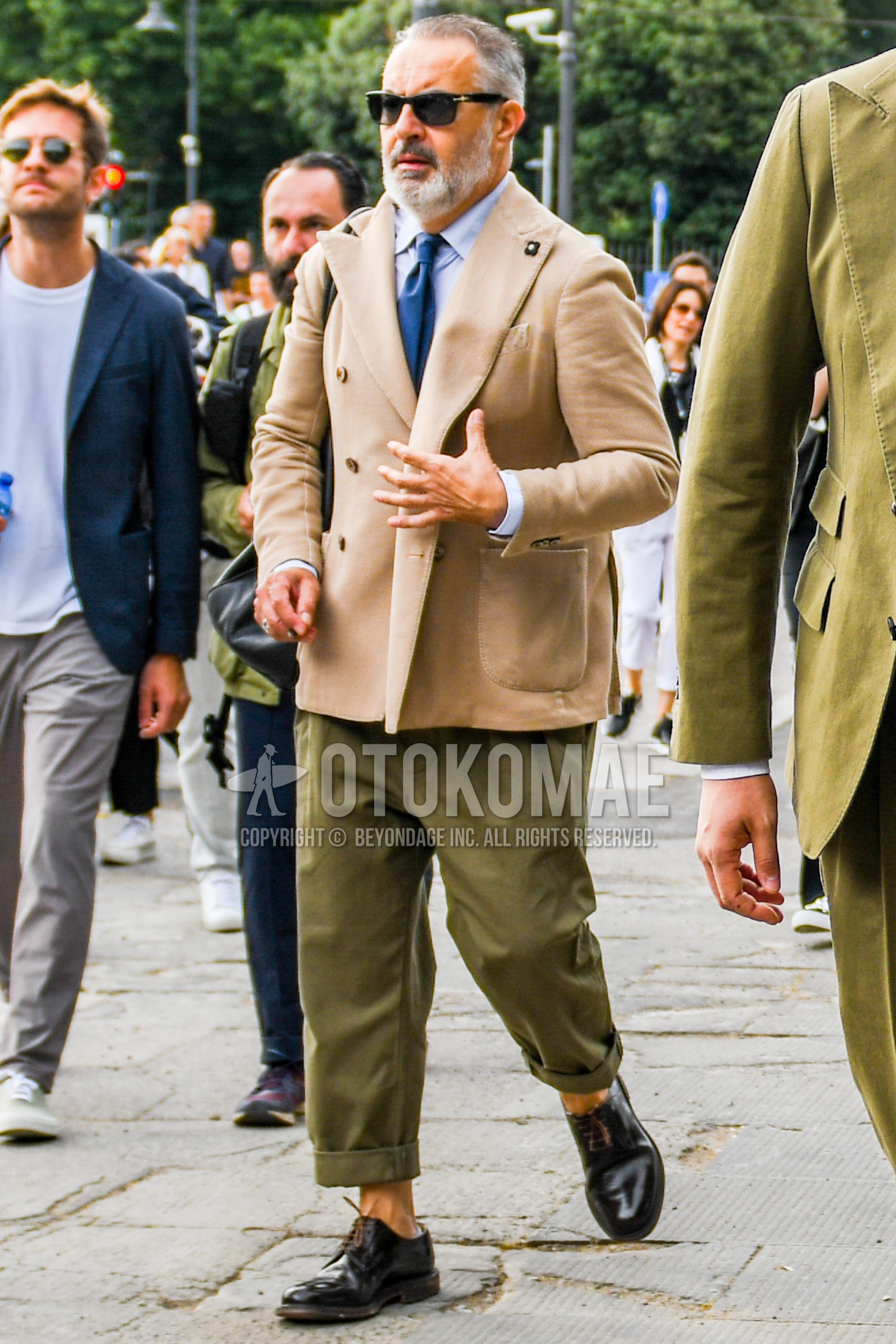 Men's spring summer autumn outfit with plain sunglasses, beige plain tailored jacket, blue plain shirt, green plain suluell pants, brown plain toe leather shoes, blue plain necktie.