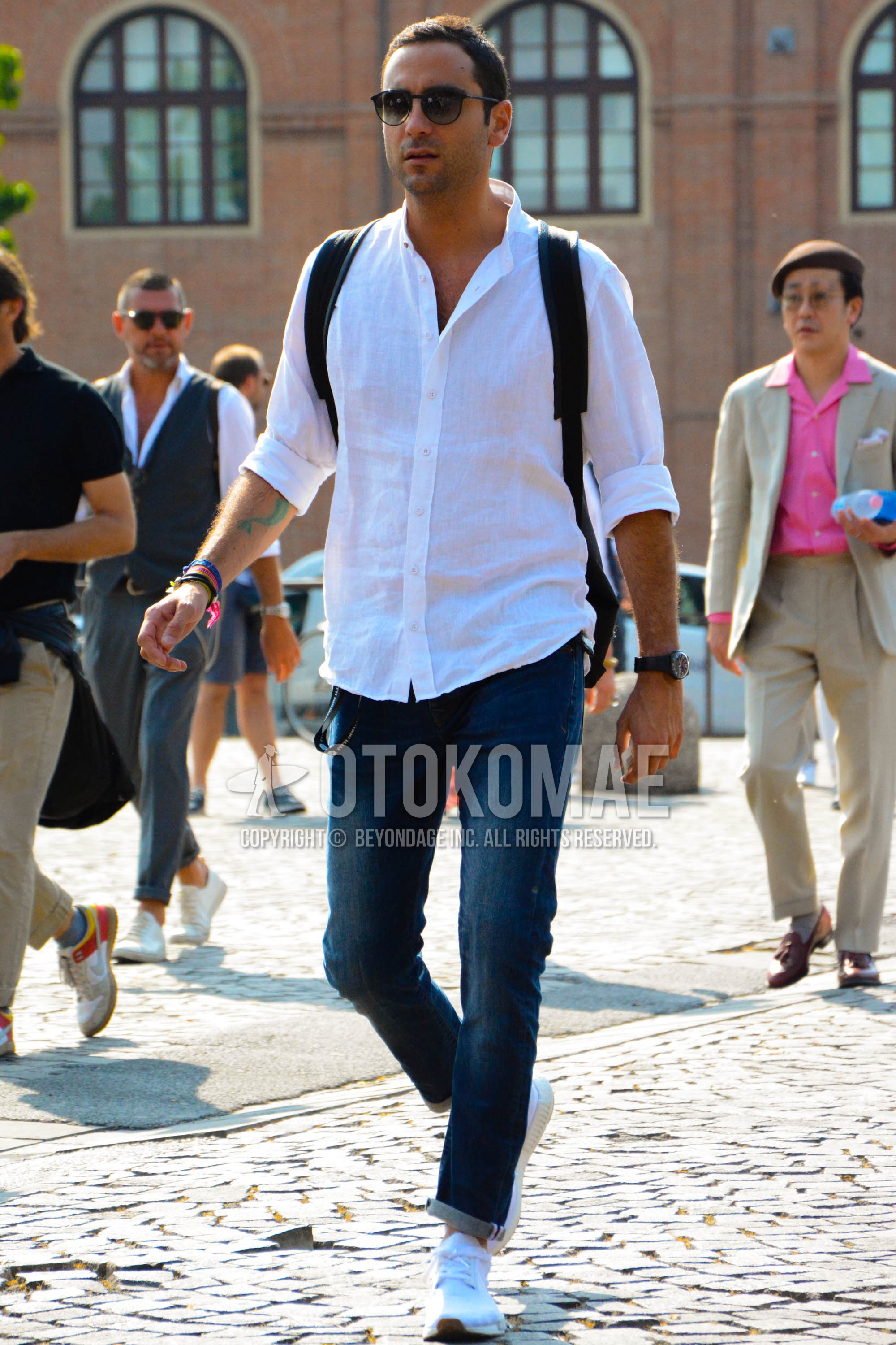 Men's spring summer outfit with black plain sunglasses, white plain shirt, blue plain denim/jeans, white low-cut sneakers.
