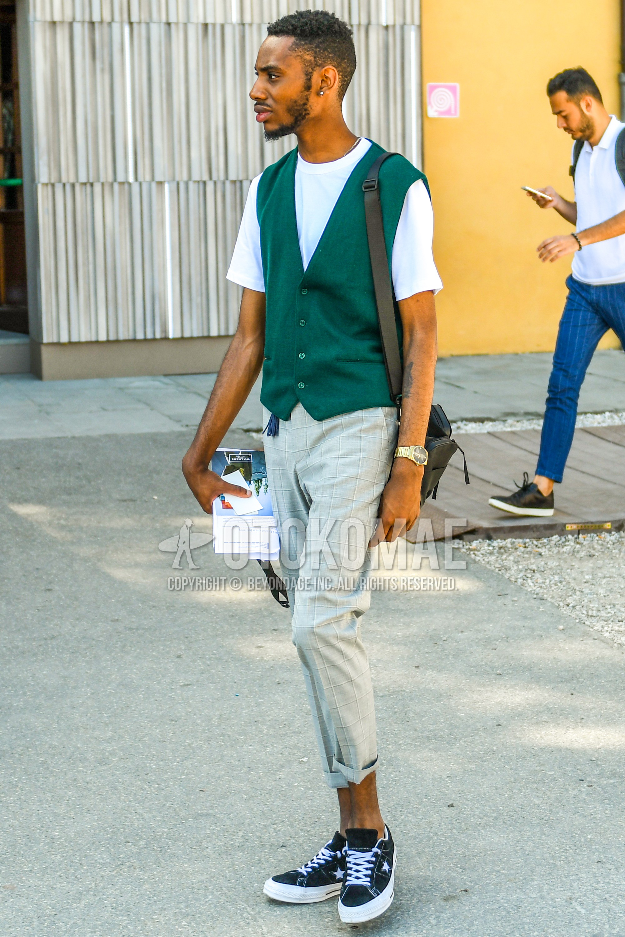 Men's summer outfit with green plain gilet, white plain t-shirt, gray check easy pants, black low-cut sneakers, brown plain shoulder bag.