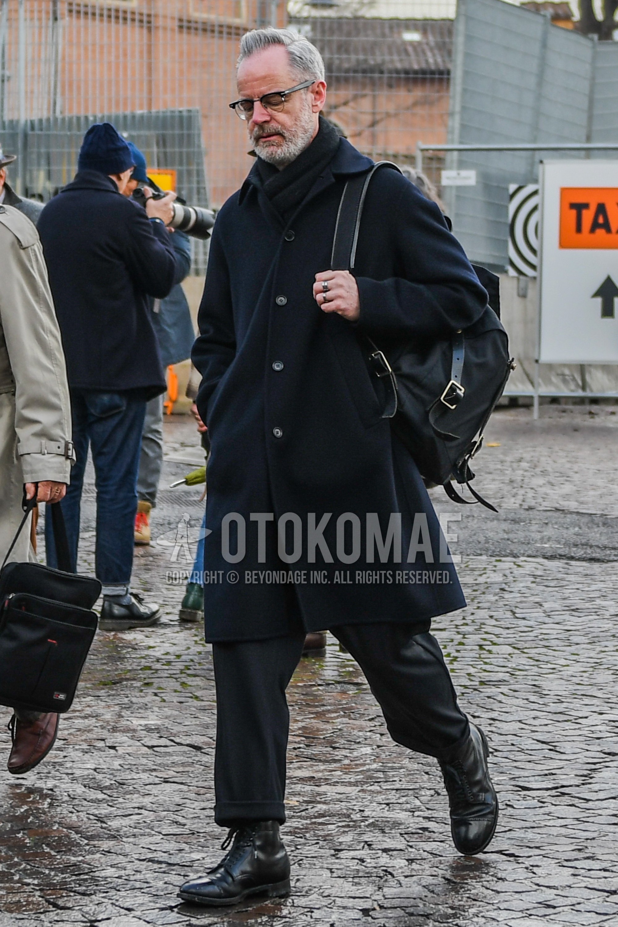 Men's winter outfit with black plain glasses, black plain scarf, black plain stenkarrer coat, plain slacks, black  boots, black plain backpack.