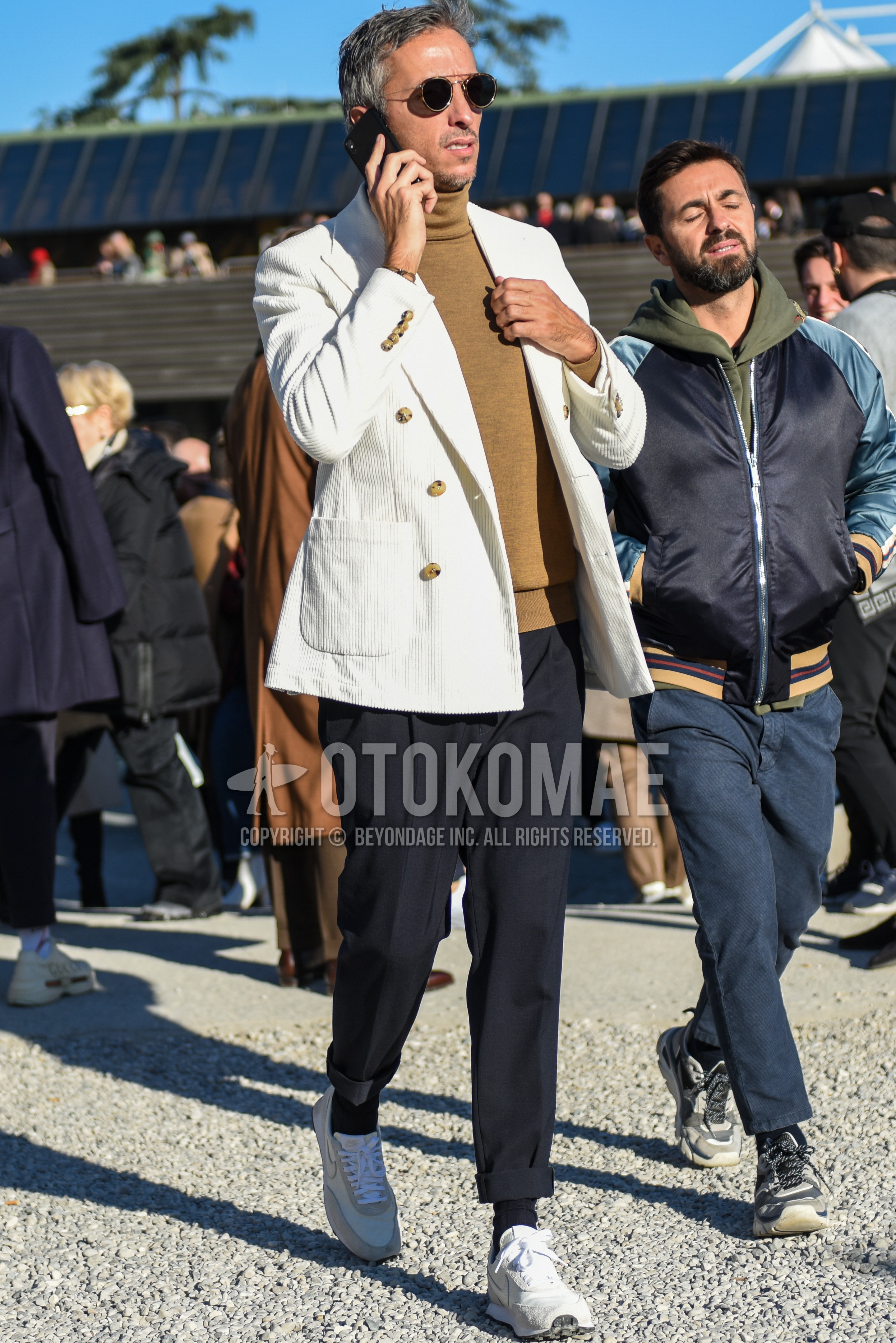 Men's spring autumn outfit with black plain sunglasses, white plain tailored jacket, beige plain turtleneck knit, gray plain slacks, black plain socks, white low-cut sneakers.