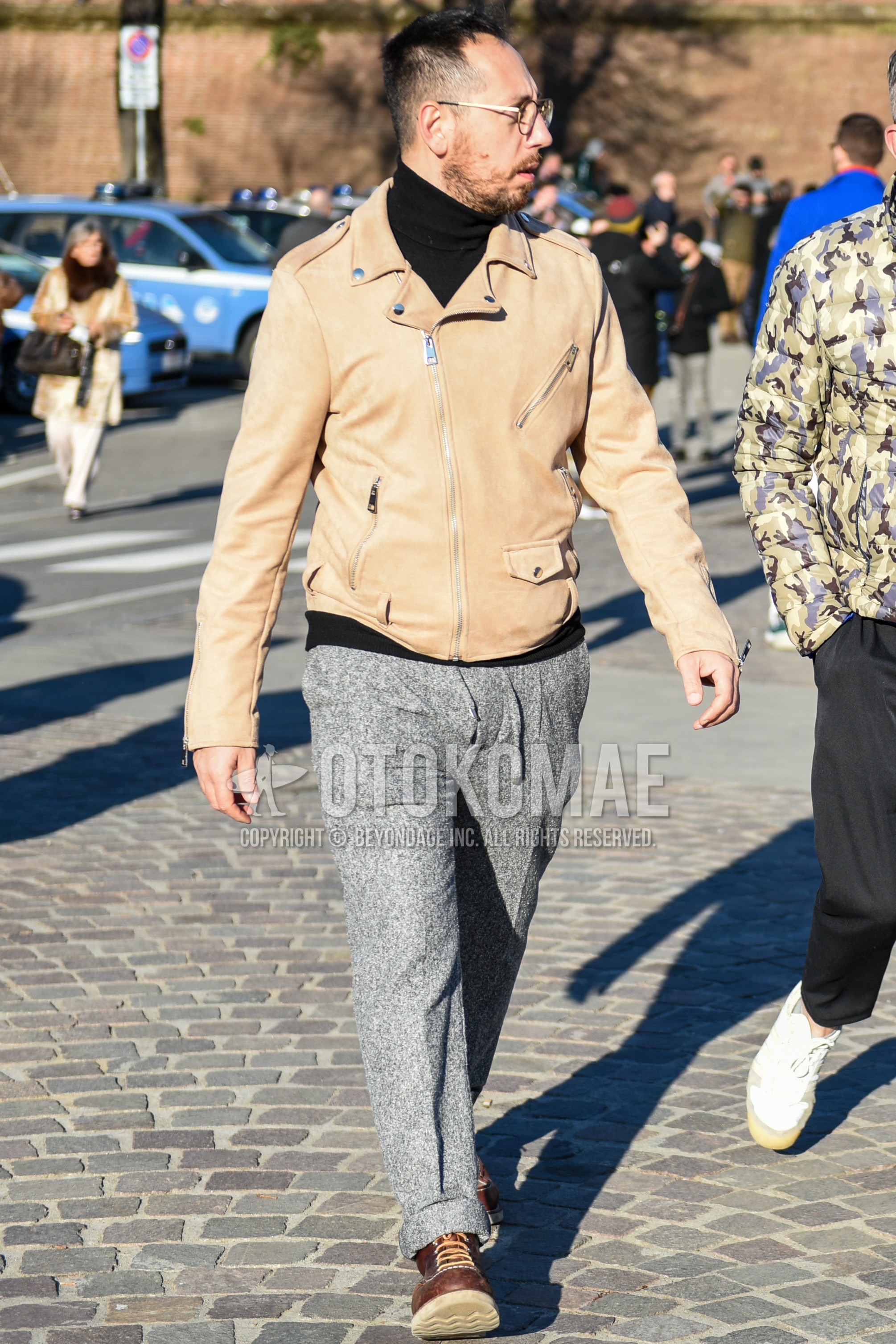 Men's autumn winter outfit with gold plain glasses, blue plain riders jacket, black plain turtleneck knit, gray plain easy pants, brown work boots.