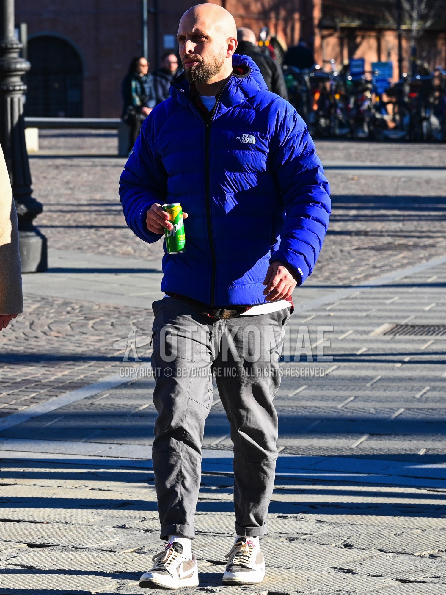 Men's autumn winter outfit with blue plain down jacket, multi-color check shirt, white plain t-shirt, gray plain work pants, white plain socks, gray low-cut sneakers.
