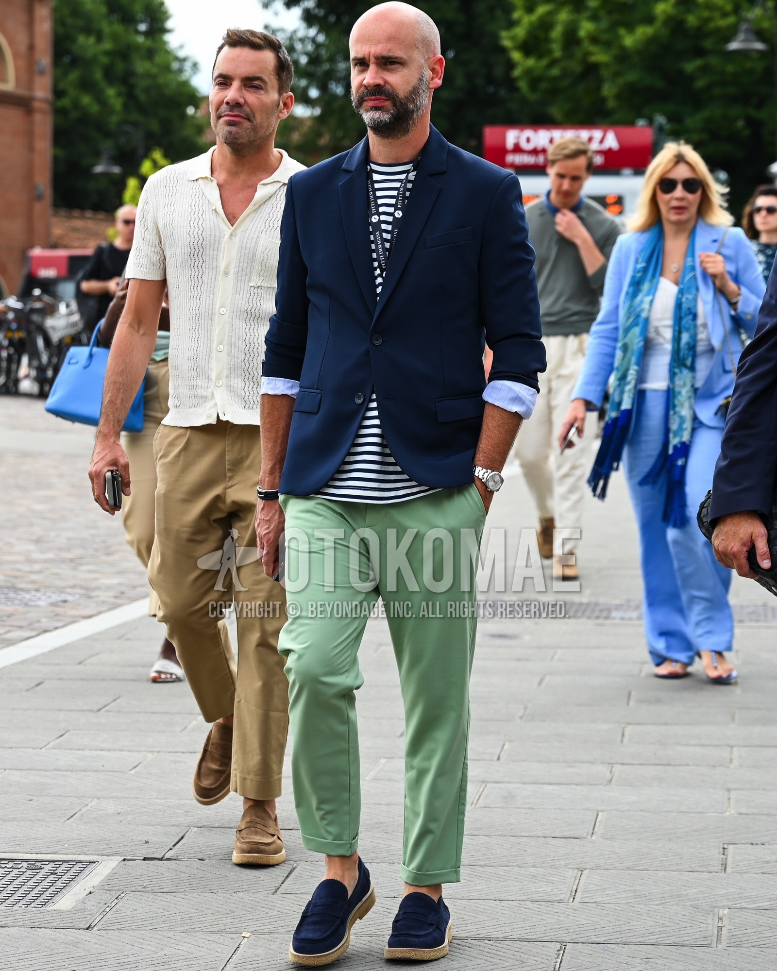 Men's spring summer autumn outfit with navy plain tailored jacket, navy horizontal stripes t-shirt, green plain chinos, navy coin loafers leather shoes.