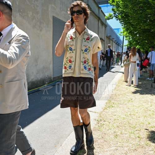 黒無地のサングラス、ベージュトップス/インナーのシャツ、ブラウン無地のイージーパンツ、ブラウン無地のショートパンツ、黒のブーツを合わせた夏のメンズコーデ・着こなし。