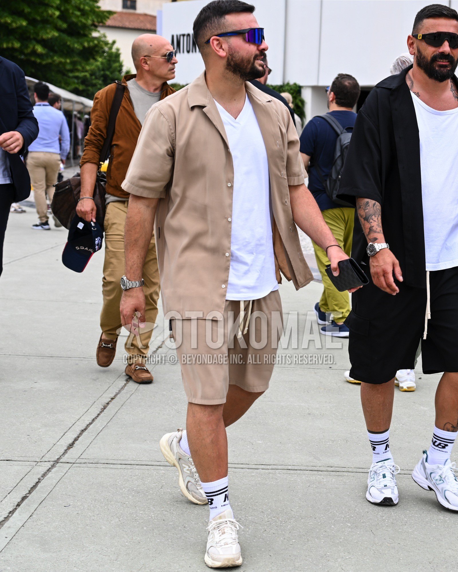 Men's spring summer outfit with blue plain sunglasses, white plain t-shirt, white one point socks, white low-cut sneakers, beige plain casual setup.