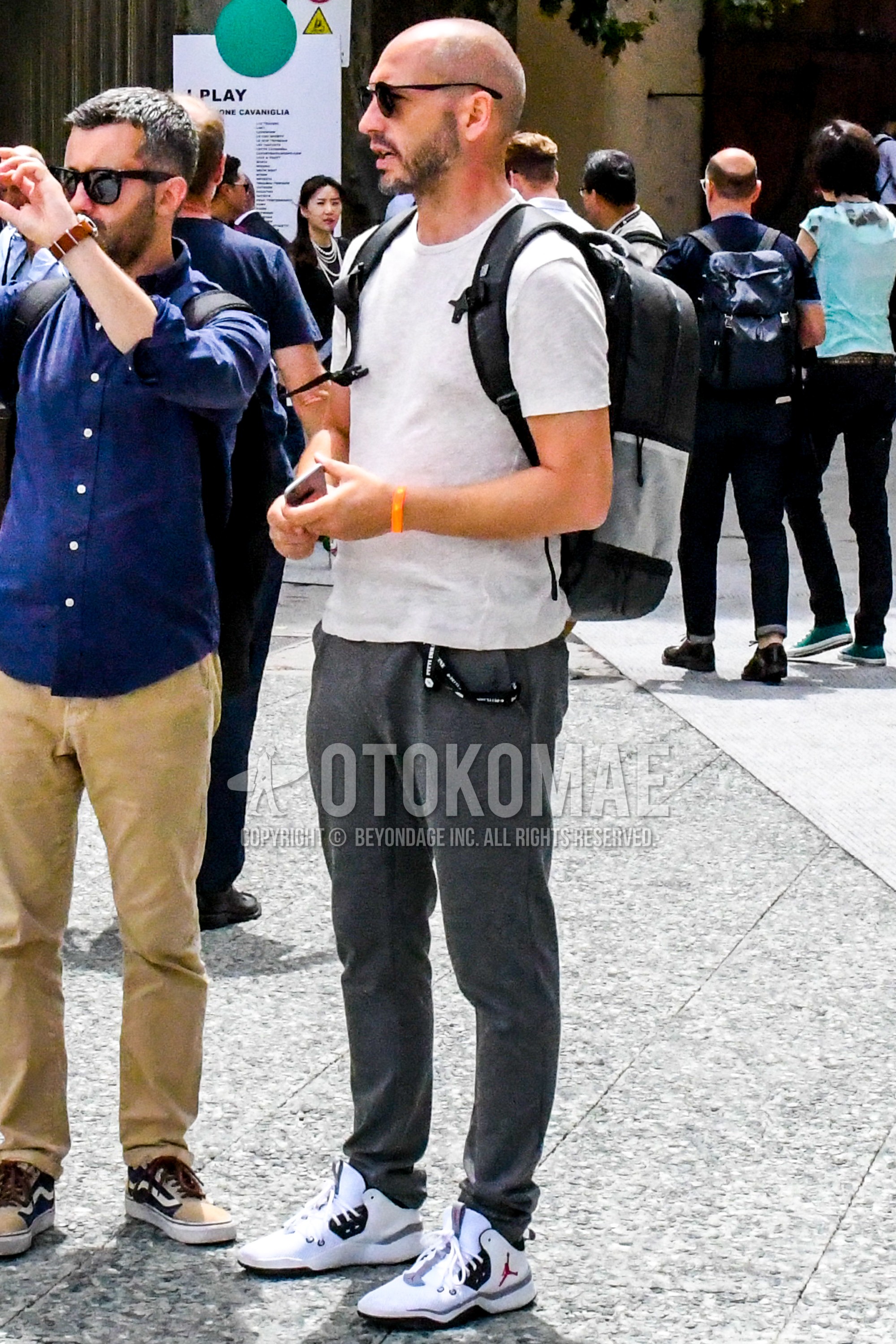 Men's summer outfit with plain sunglasses, white plain t-shirt, gray plain cotton pants, white high-cut sneakers, black gray plain backpack.