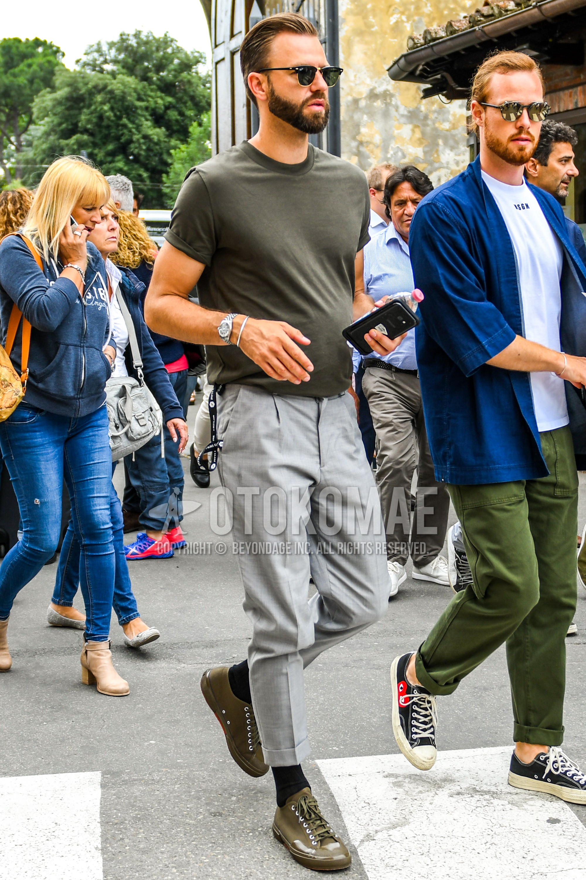 Men's summer outfit with plain sunglasses, olive green plain t-shirt, gray plain pleated pants, black plain socks, olive green low-cut sneakers.