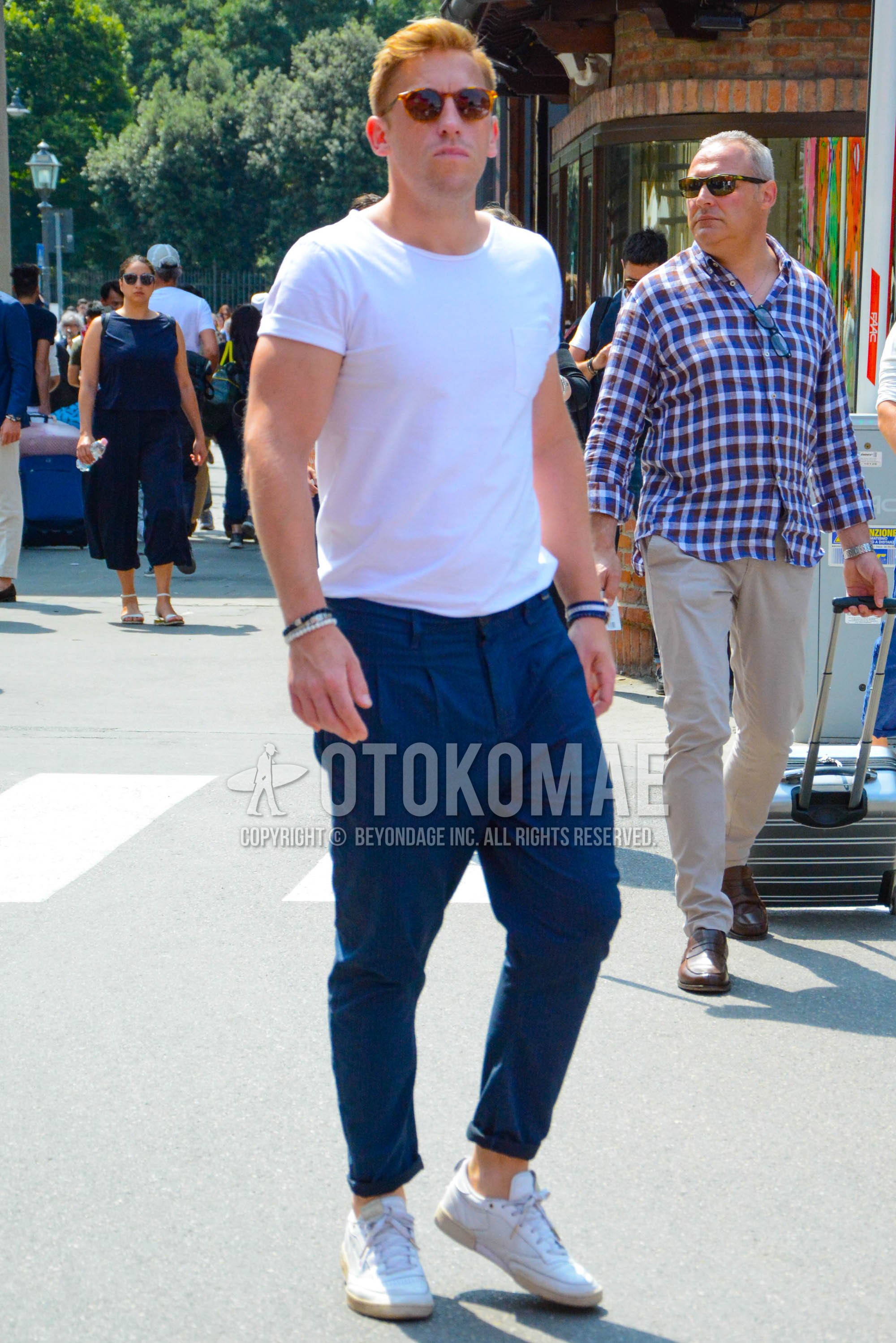 Men's spring summer outfit with brown tortoiseshell sunglasses, white plain t-shirt, navy stripes cotton pants, navy stripes pleated pants, white low-cut sneakers.