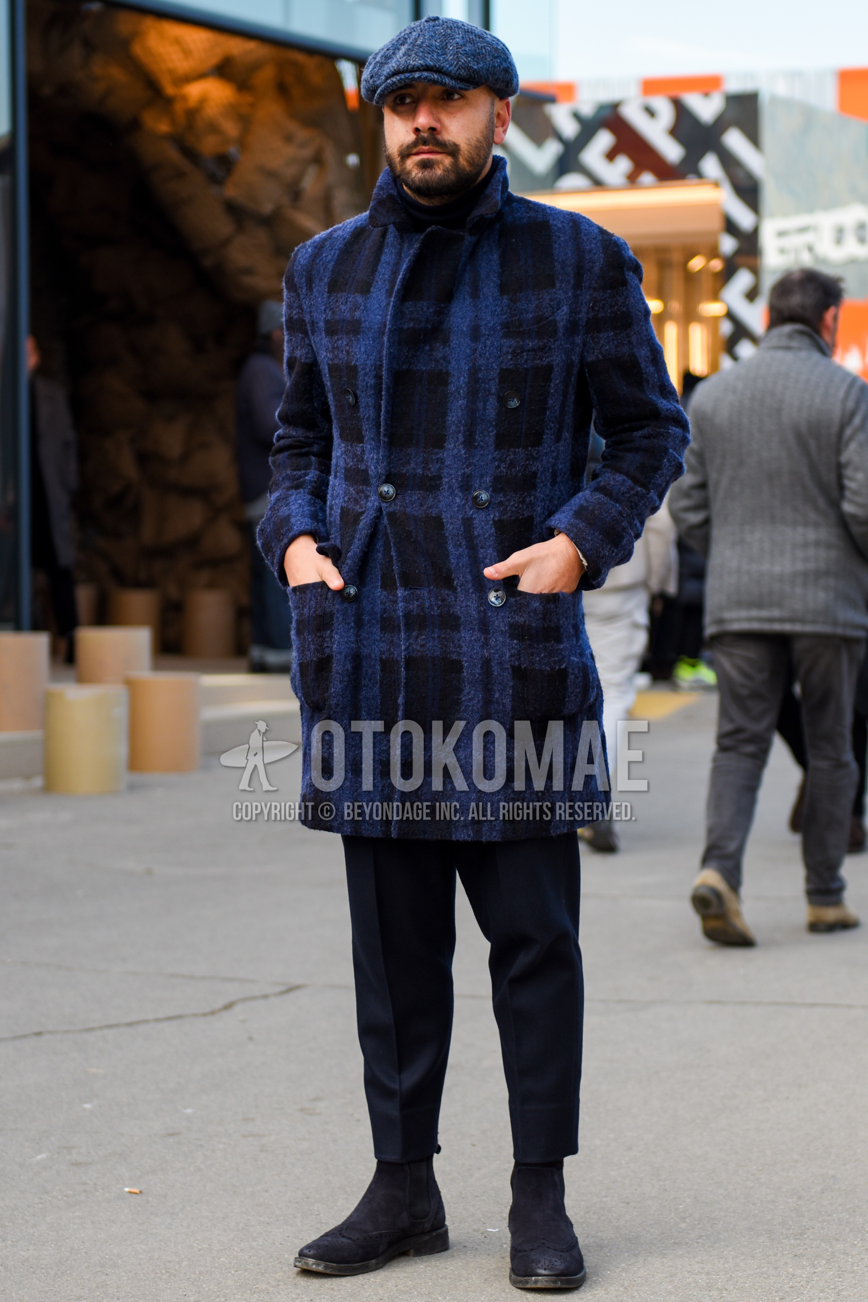 Men's autumn winter outfit with blue herringbone hunting cap, blue black check chester coat, navy plain slacks, navy plain cropped pants, navy side-gore boots.