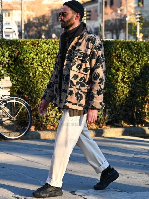 黒無地のニットキャップ、黒・ゴールド無地のサングラス、ベージュ・黒グラフィックのミリタリージャケット(MA-1、M-65以外)、ブラウン無地のテーラードジャケット、ダークグレー無地のタートルネックニット、ベージュ・黒ストライプのシャツ、白無地のチノパン、黒ドットのソックス、黒ローカットのスニーカーを合わせた秋冬のメンズコーデ・着こなし。
