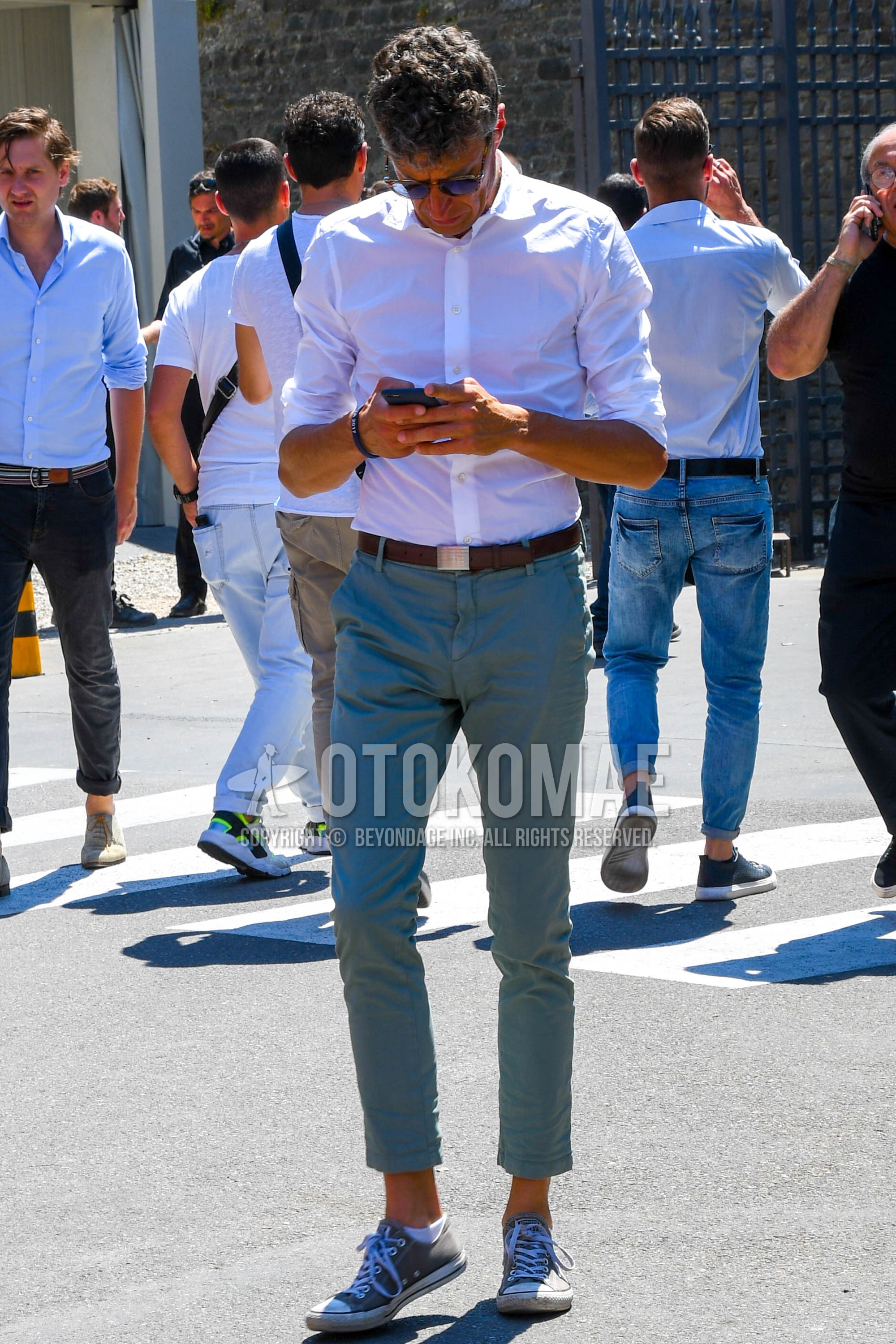 Men's spring summer outfit with plain sunglasses, white plain shirt, brown plain leather belt, gray plain cropped pants, plain cotton pants, gray low-cut sneakers.